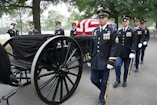 Soldiers carry a casket in a military funeral procession.