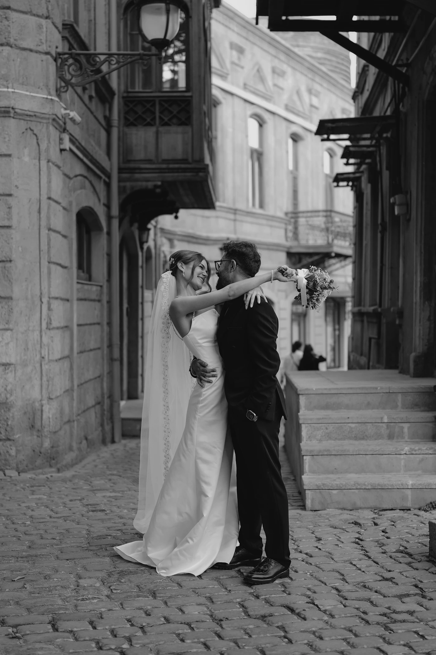 Couple at a small cafe table in Petit-Champlain in Quebec City after their elopement ceremony with the historic stone building and the cobblestone pedestrian street visible through the window or outside