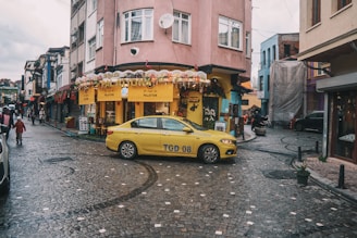 A yellow taxi drives through a busy city street.