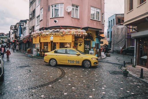 A yellow taxi drives through a busy city street.
