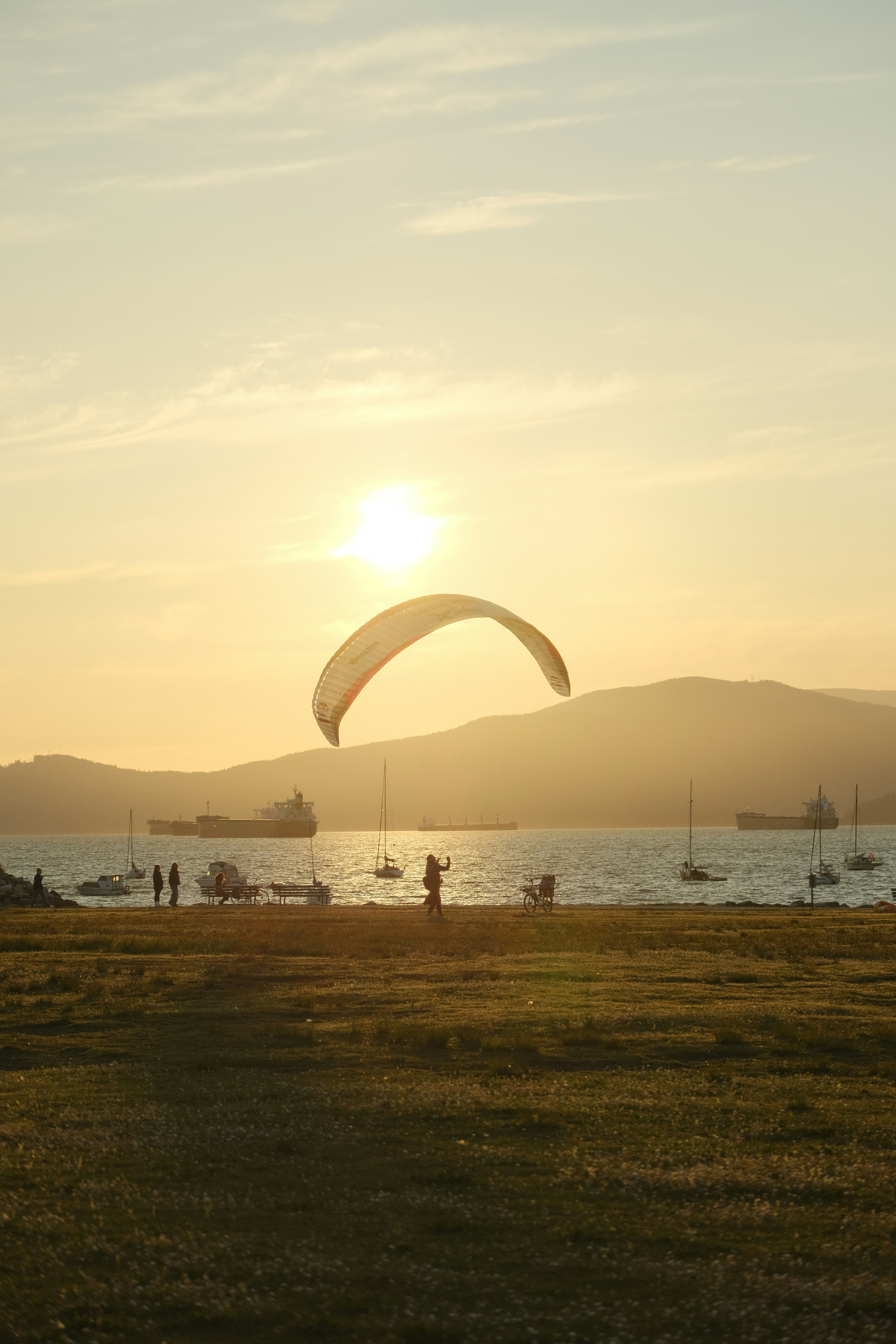 A paraglider soars at sunset over the sea.
