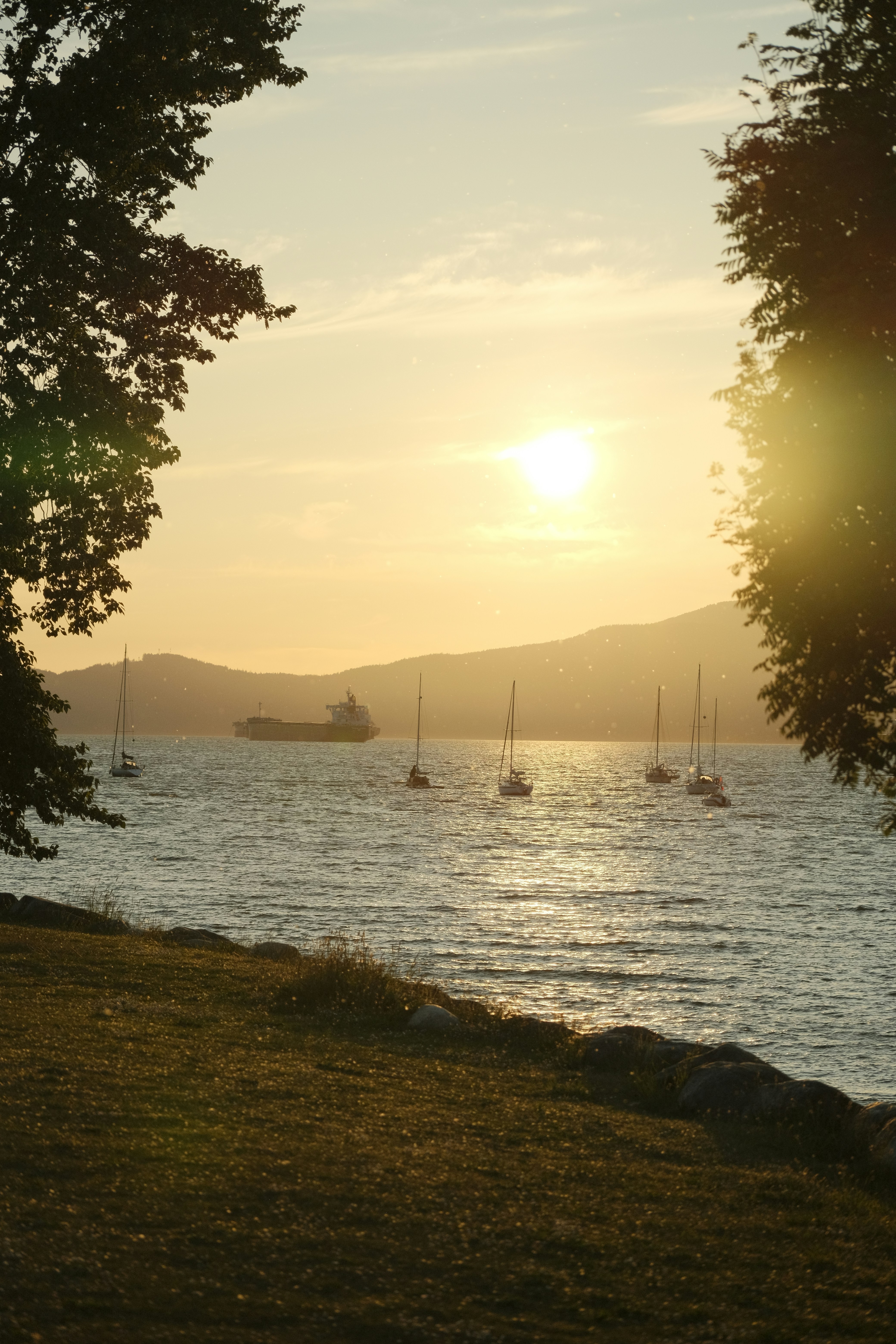 Boats sail on the water at sunset.