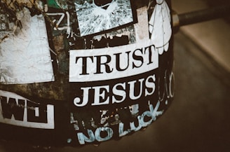 A sticker says "trust jesus" on a worn surface.