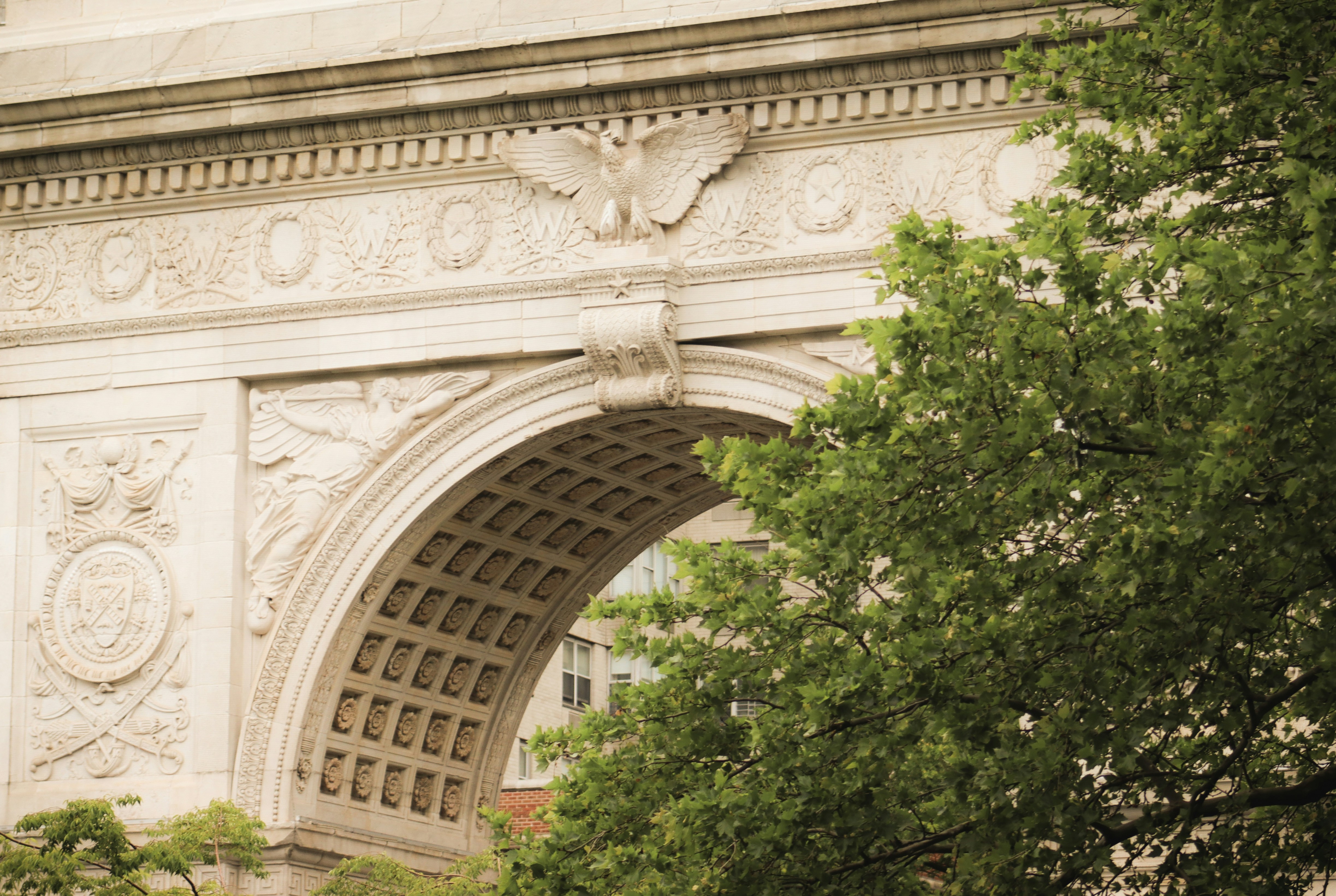 An ornate archway is partially framed by trees.