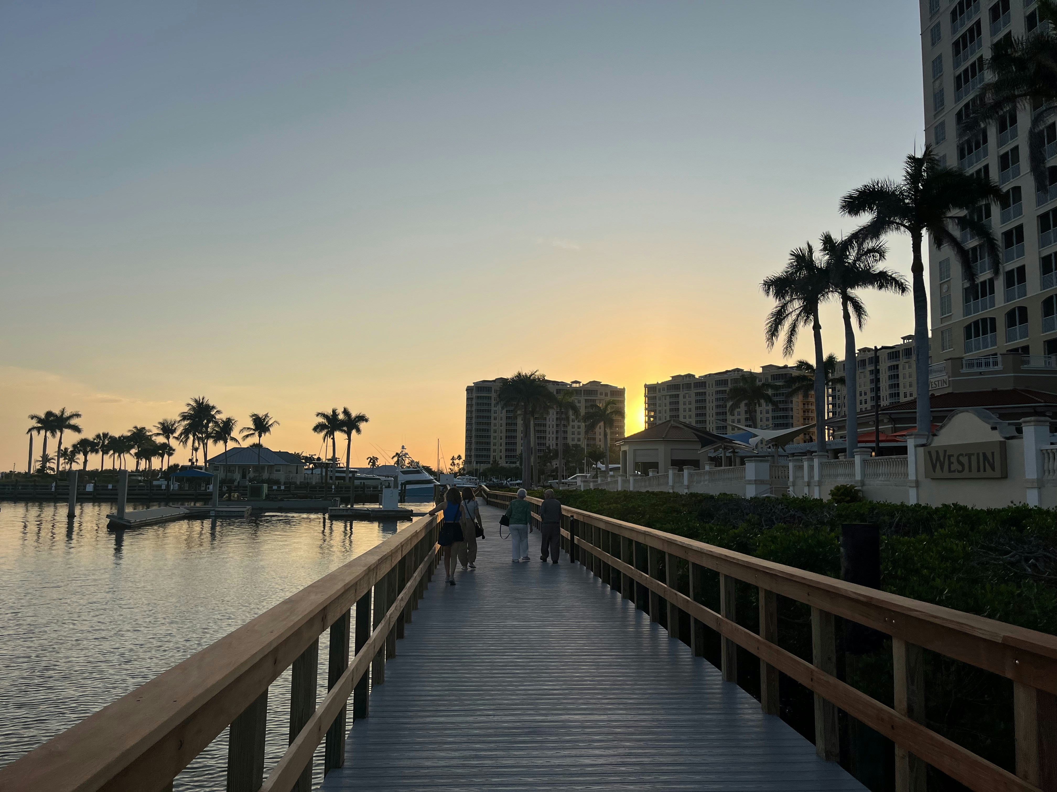 A pier at sunset with buildings in the background.