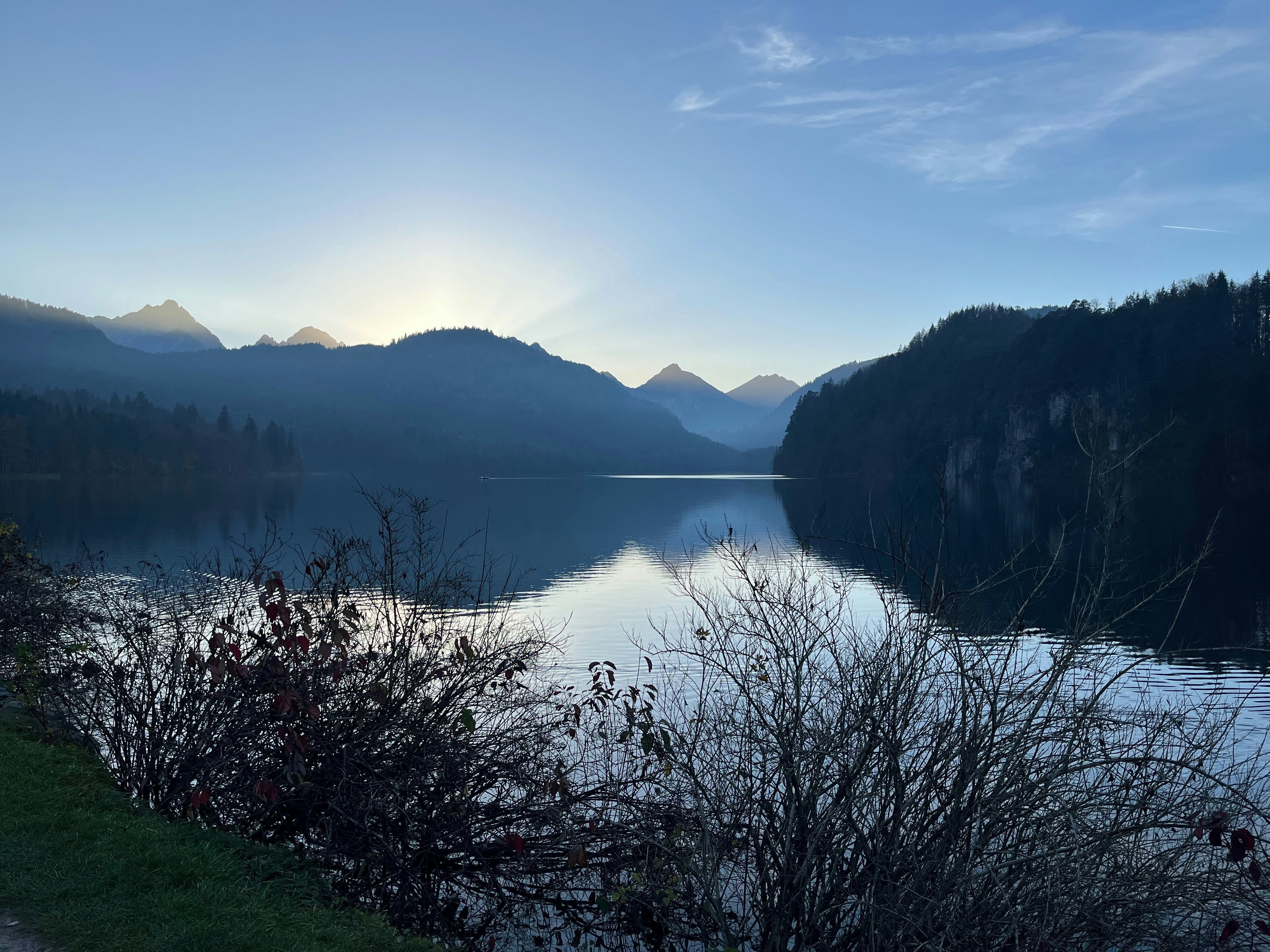 A serene lake reflects the misty mountain landscape.