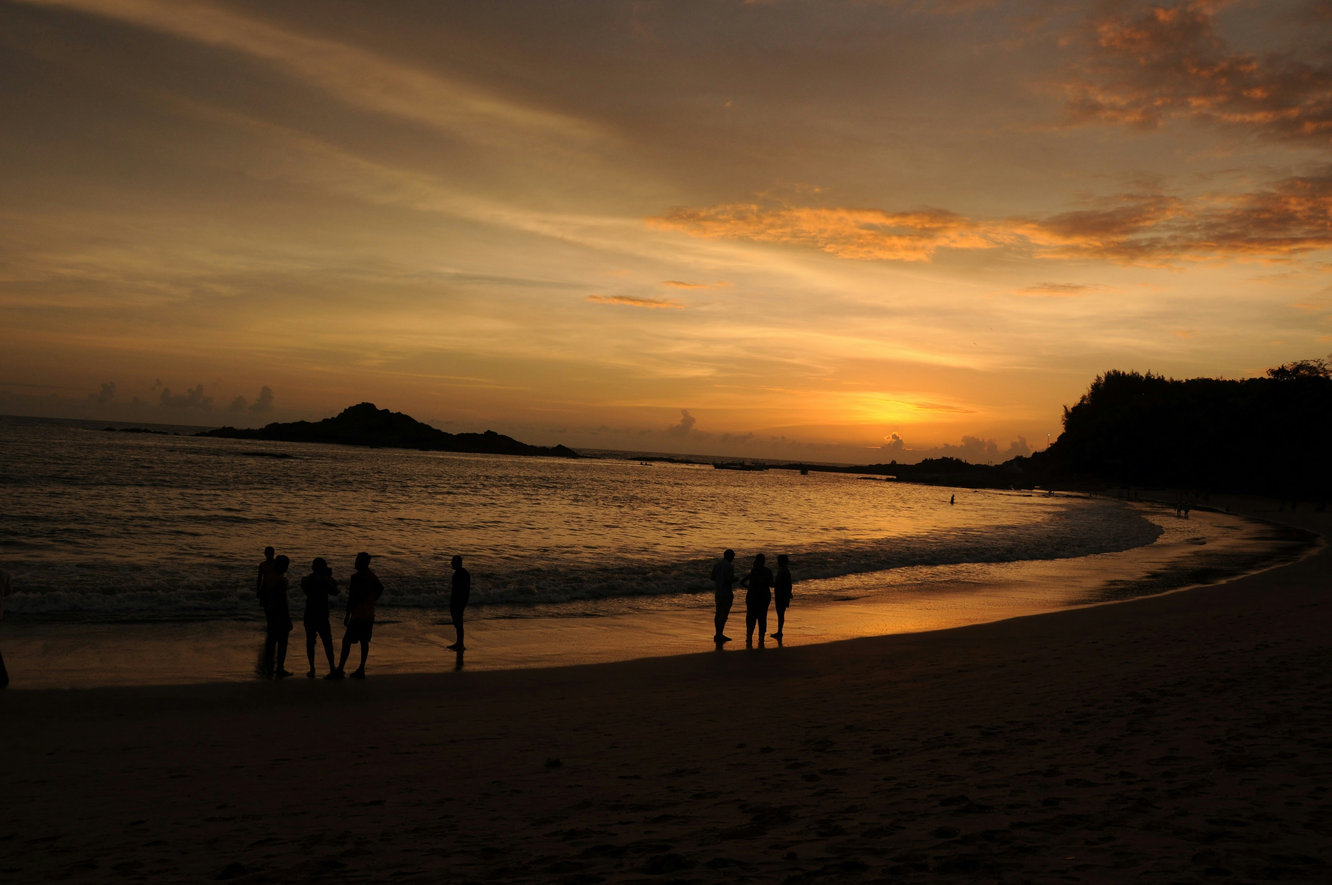 People watch the sunset at a beach.