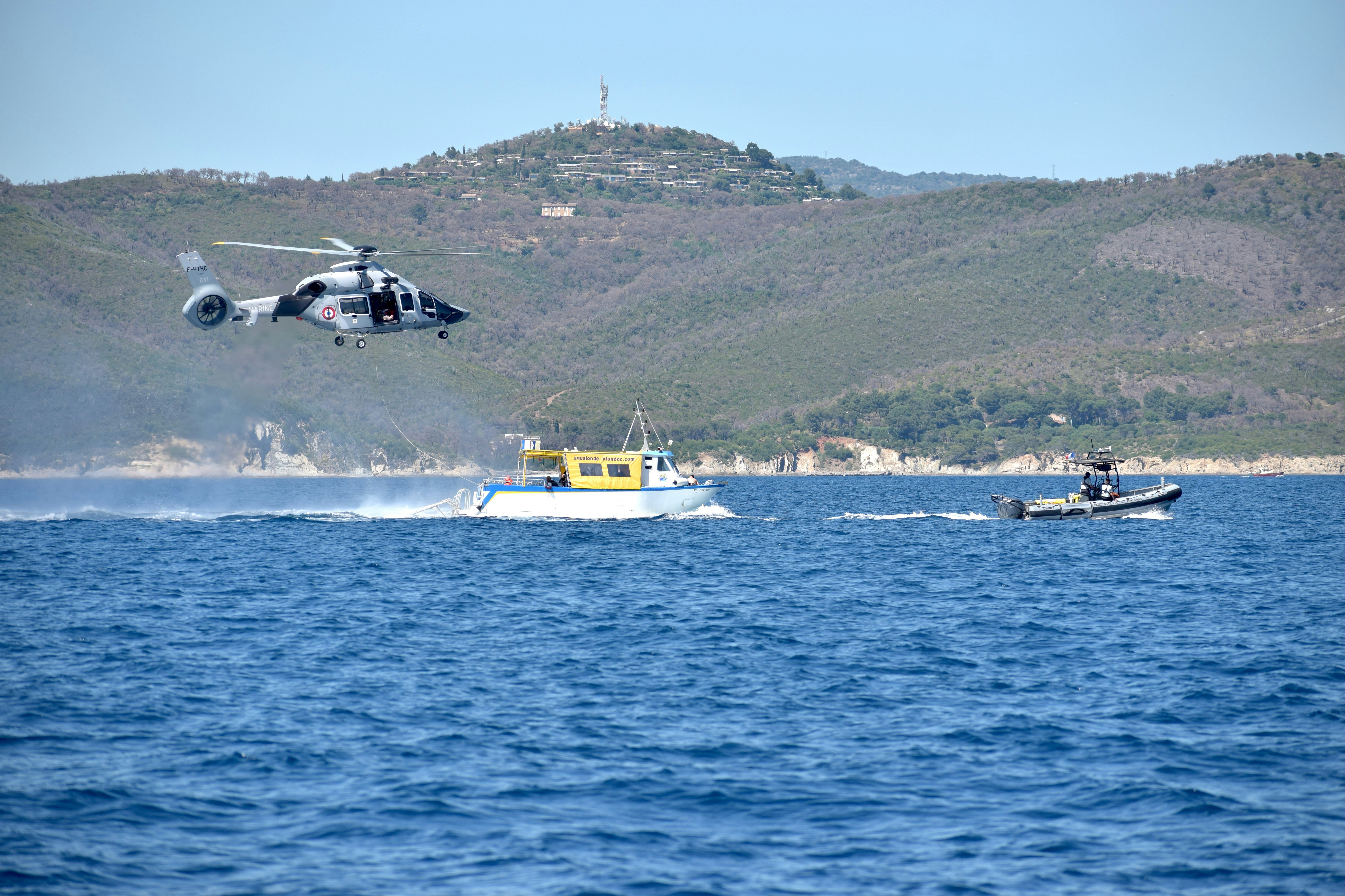 A helicopter flies over boats on the water.