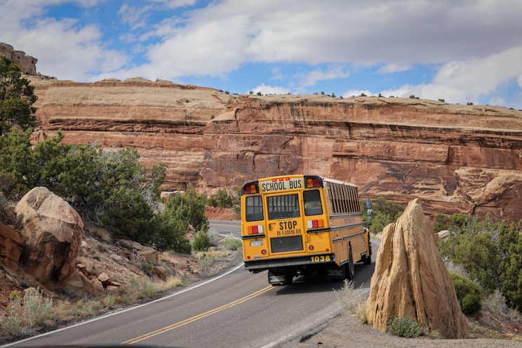 A school bus travels down a desert road.