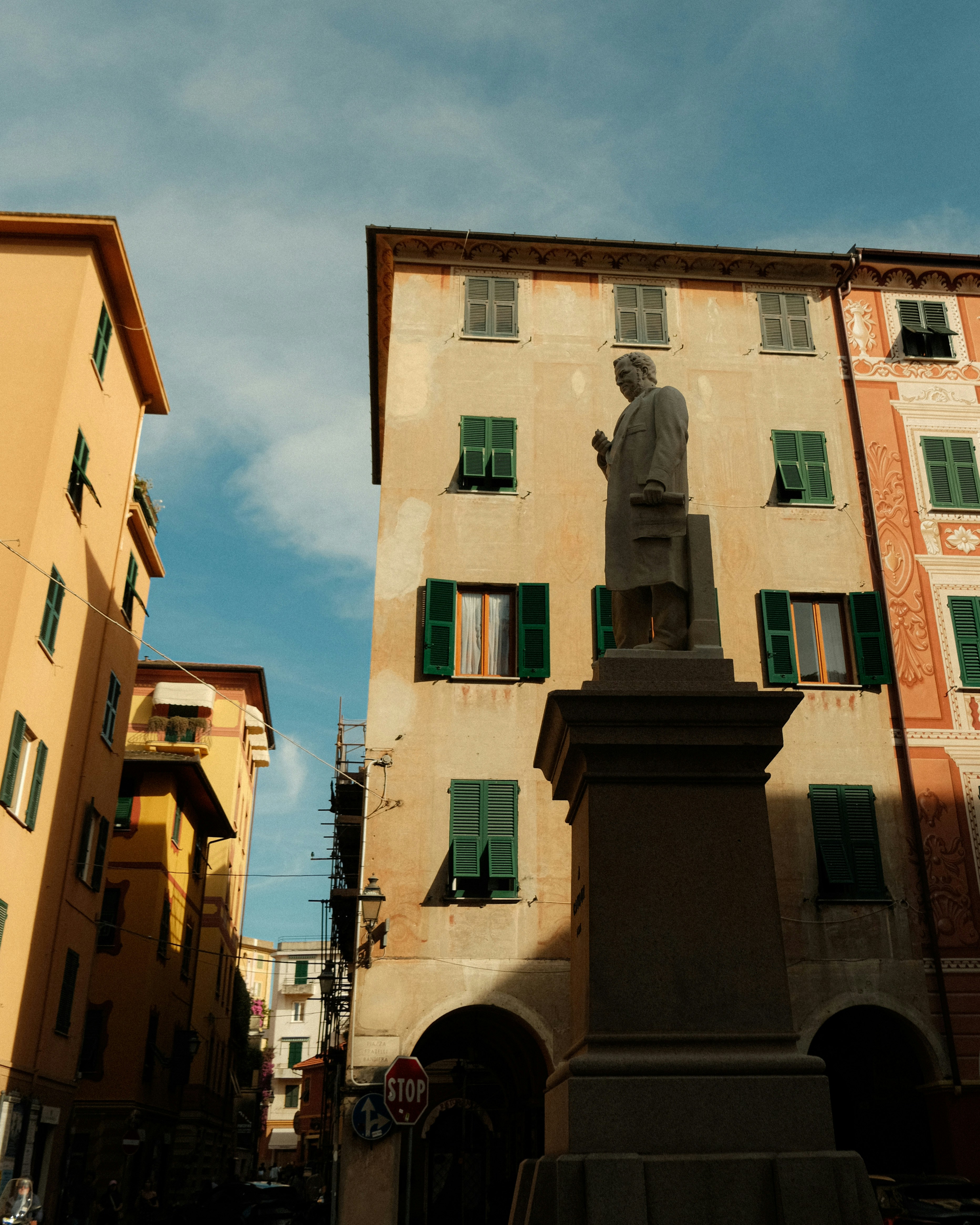 A statue stands between colorful buildings on a street