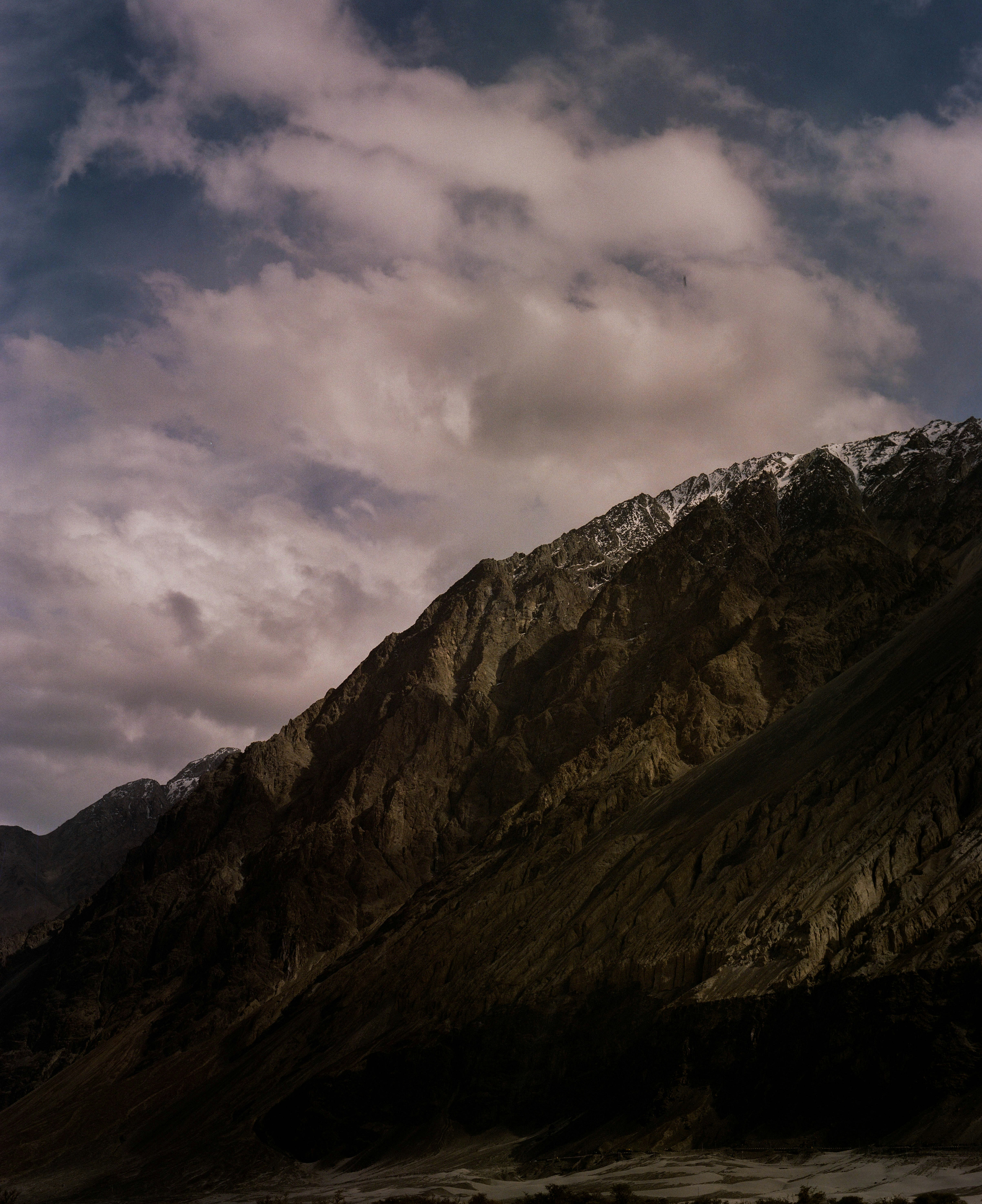 Mountains tower under a cloudy sky.