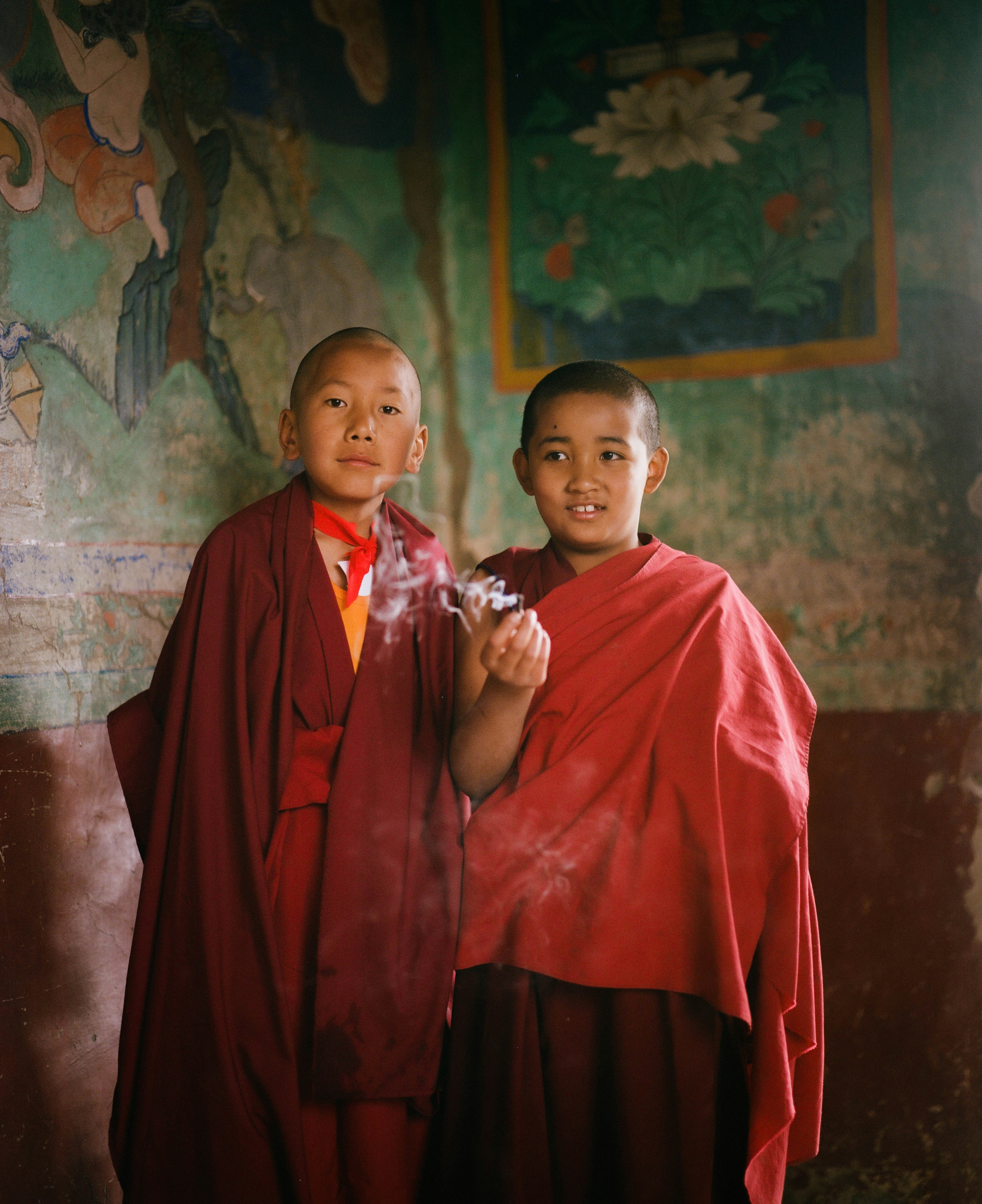 Two young buddhist monks stand together.