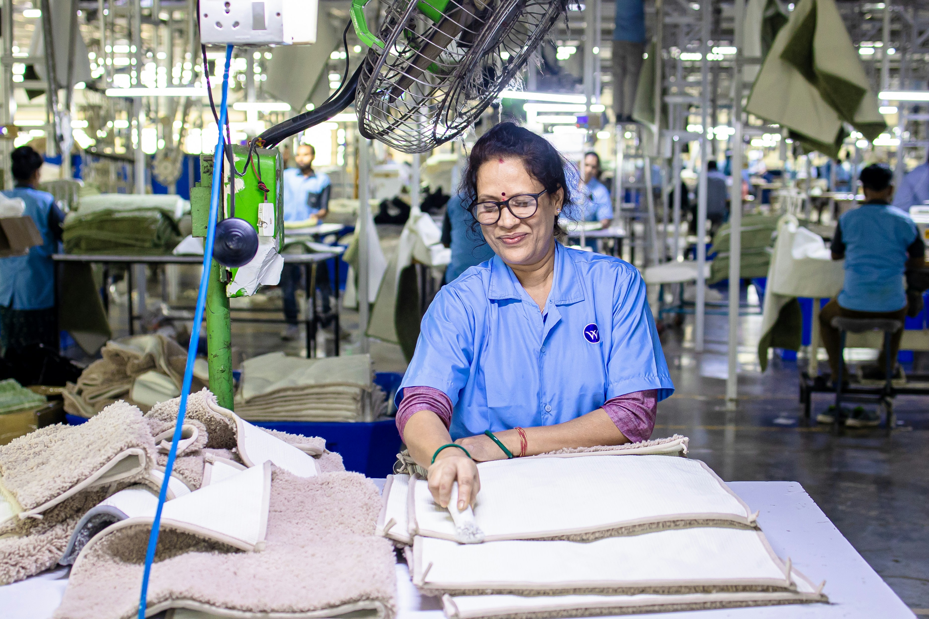A woman works at a carpet manufacturing factory.