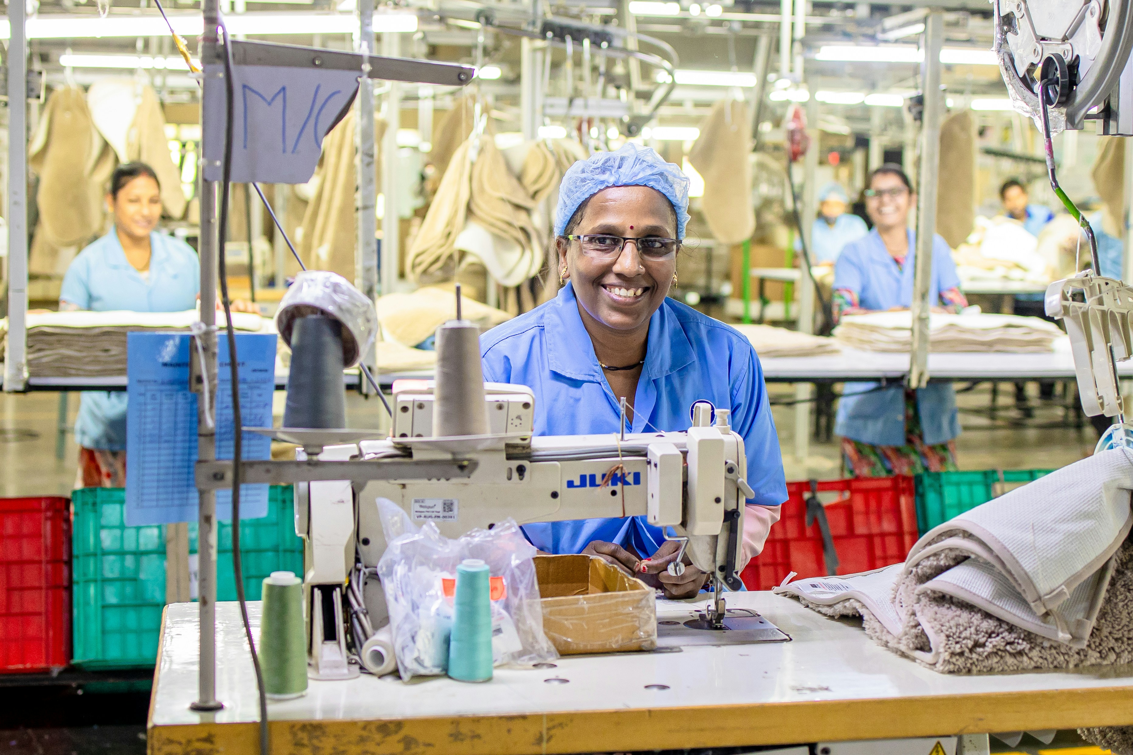 Workers are smiling while sewing in a factory.