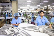 Workers assemble textiles in a bustling factory.