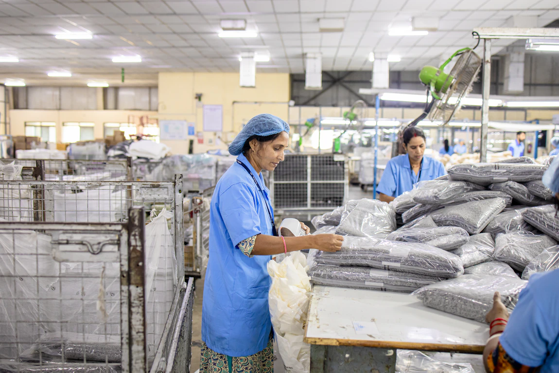 Workers sorting and packaging items at a factory — illustrative photograph