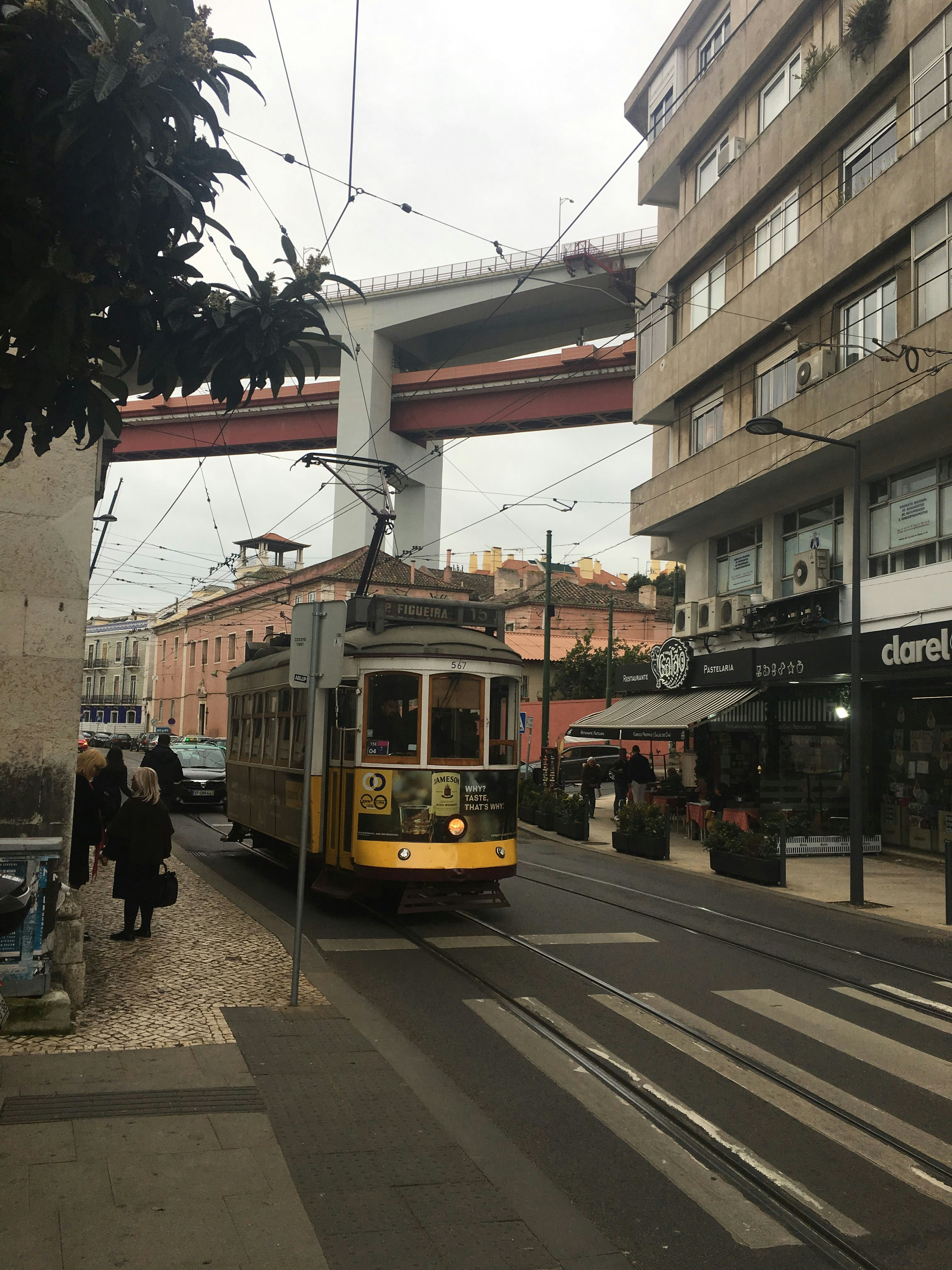 A yellow tram is in a city street.