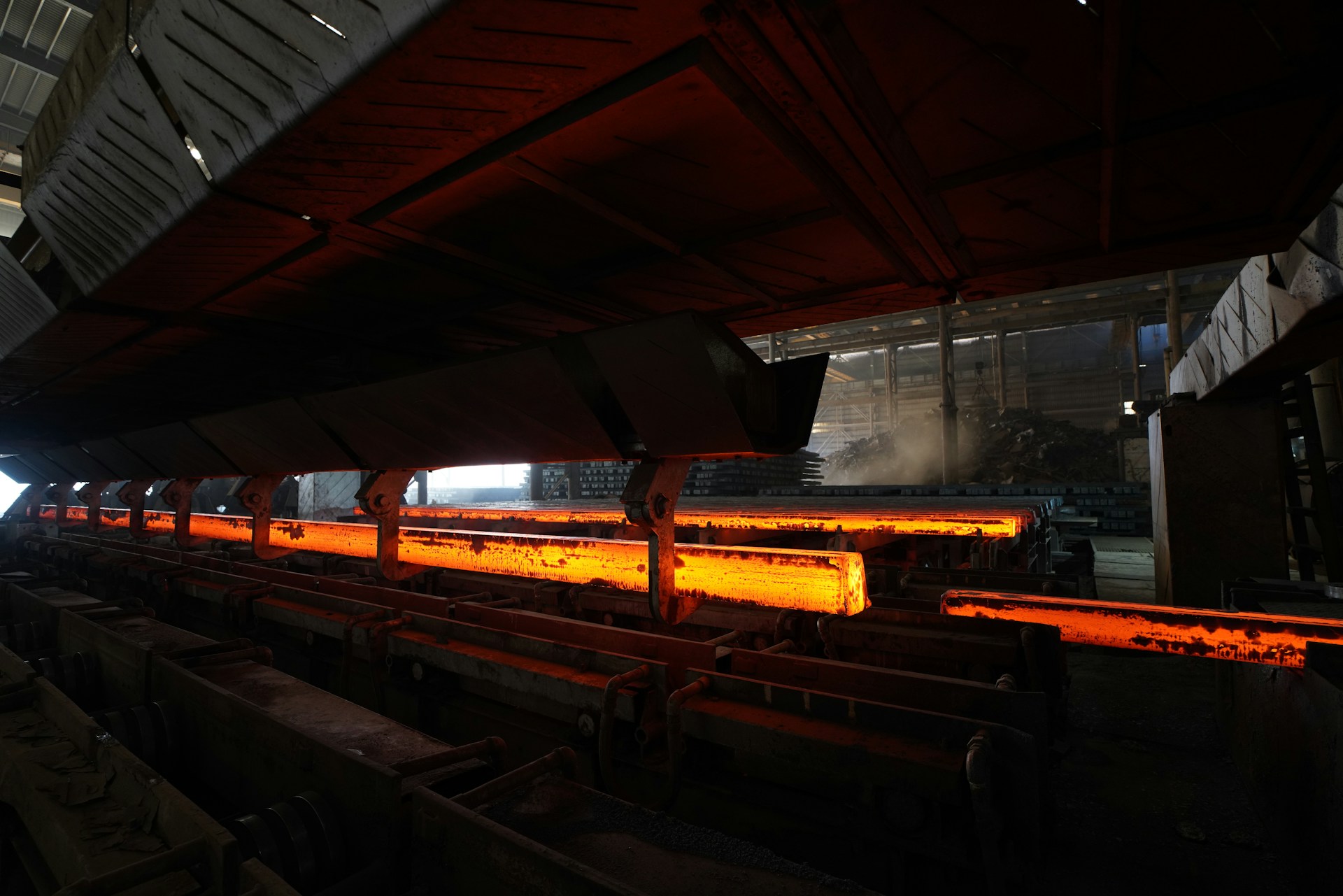 Glowing metal rods are being processed in a factory.