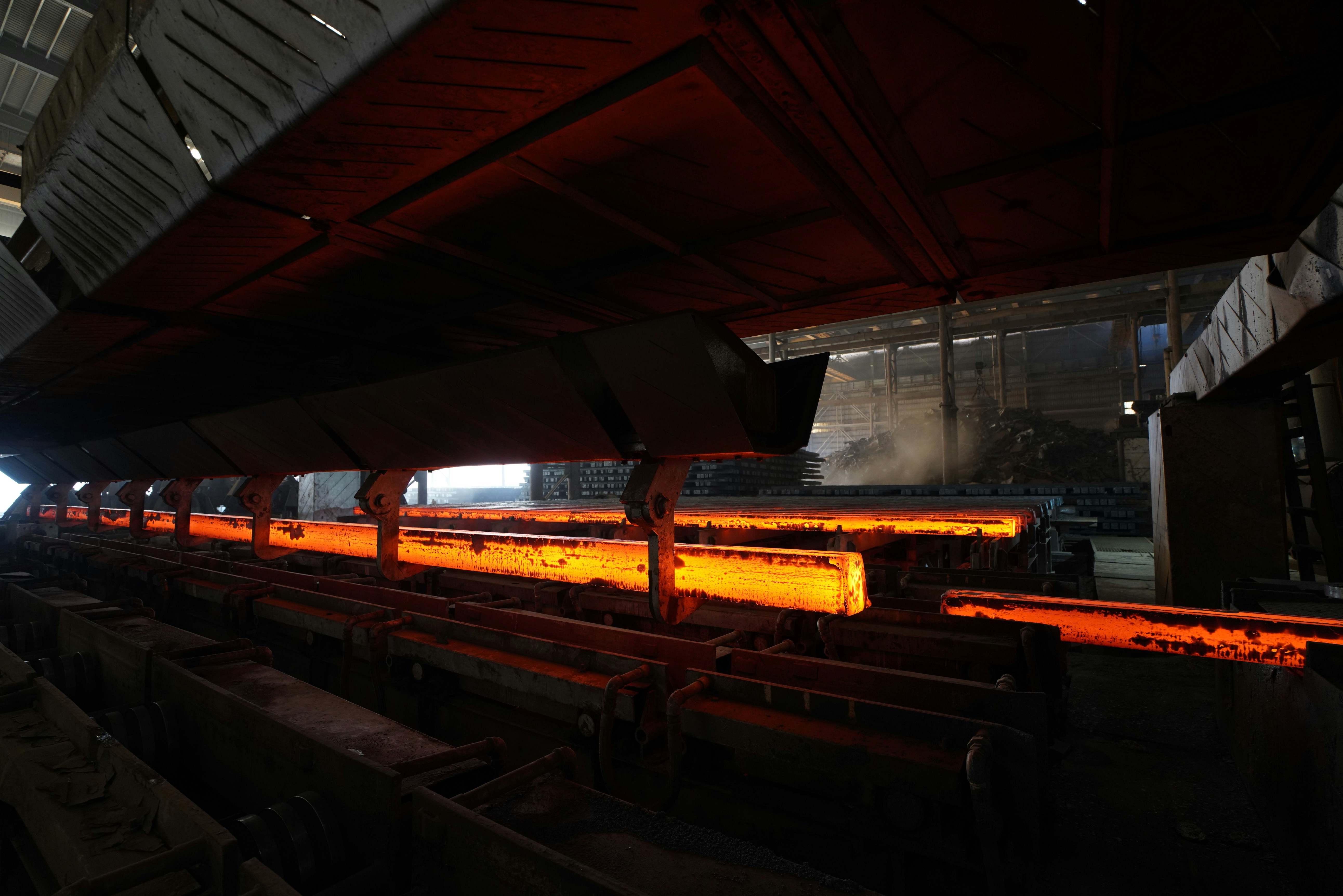 Glowing metal rods are being processed in a factory