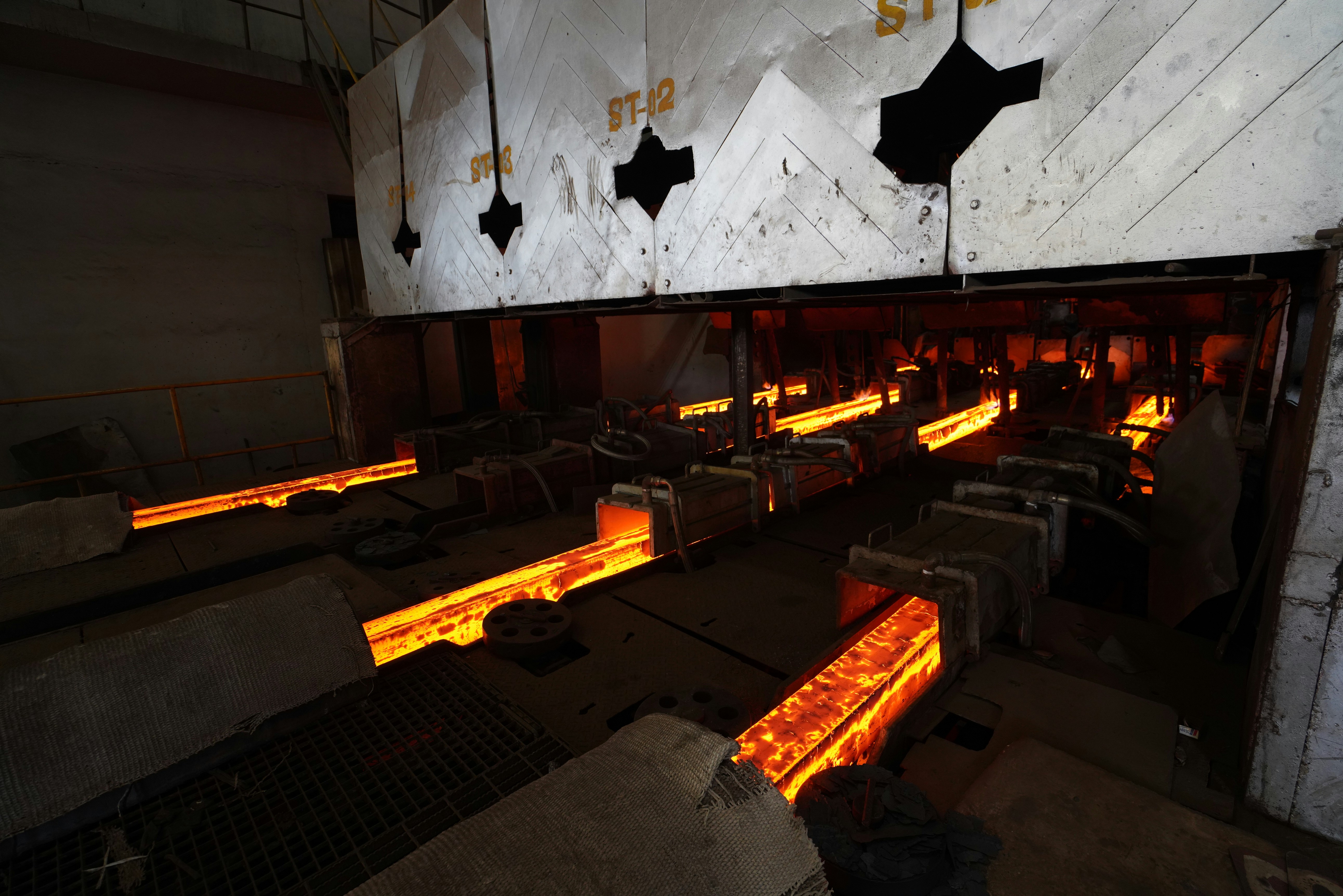 Molten steel rods move through a factory.