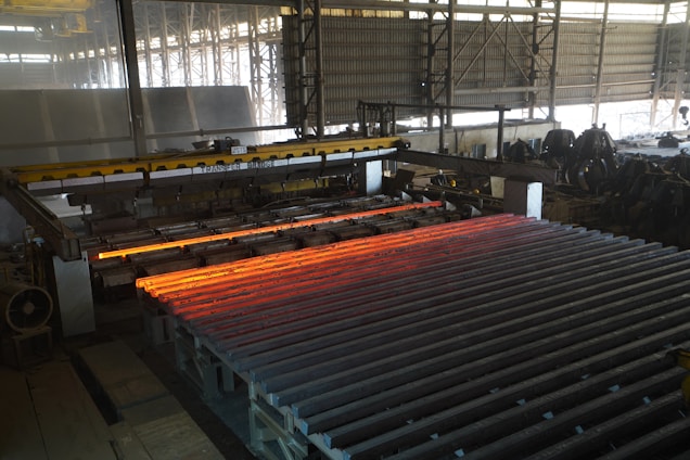 Hot steel bars are processed in a factory.