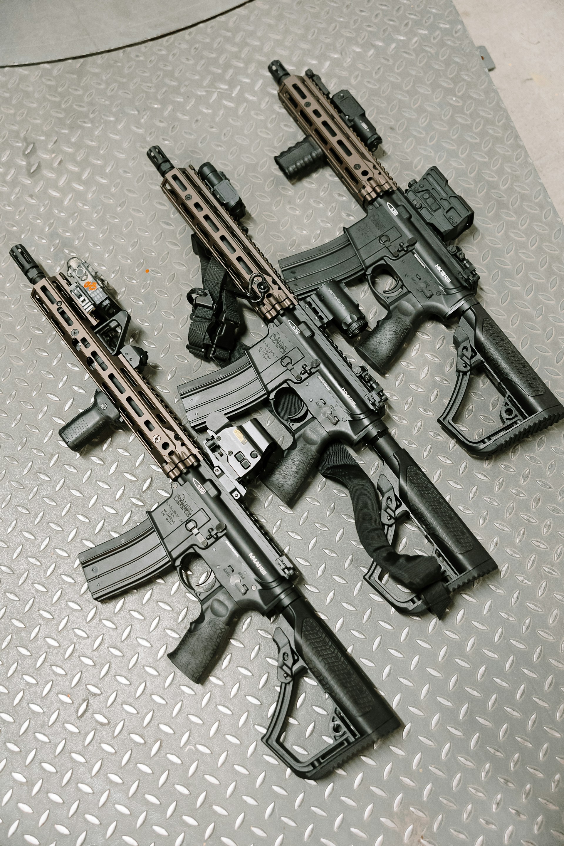 Three assault rifles sit side by side.