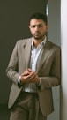 Man leans against a wall wearing a suit.