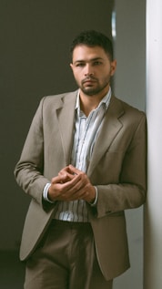 Man leans against a wall wearing a suit.