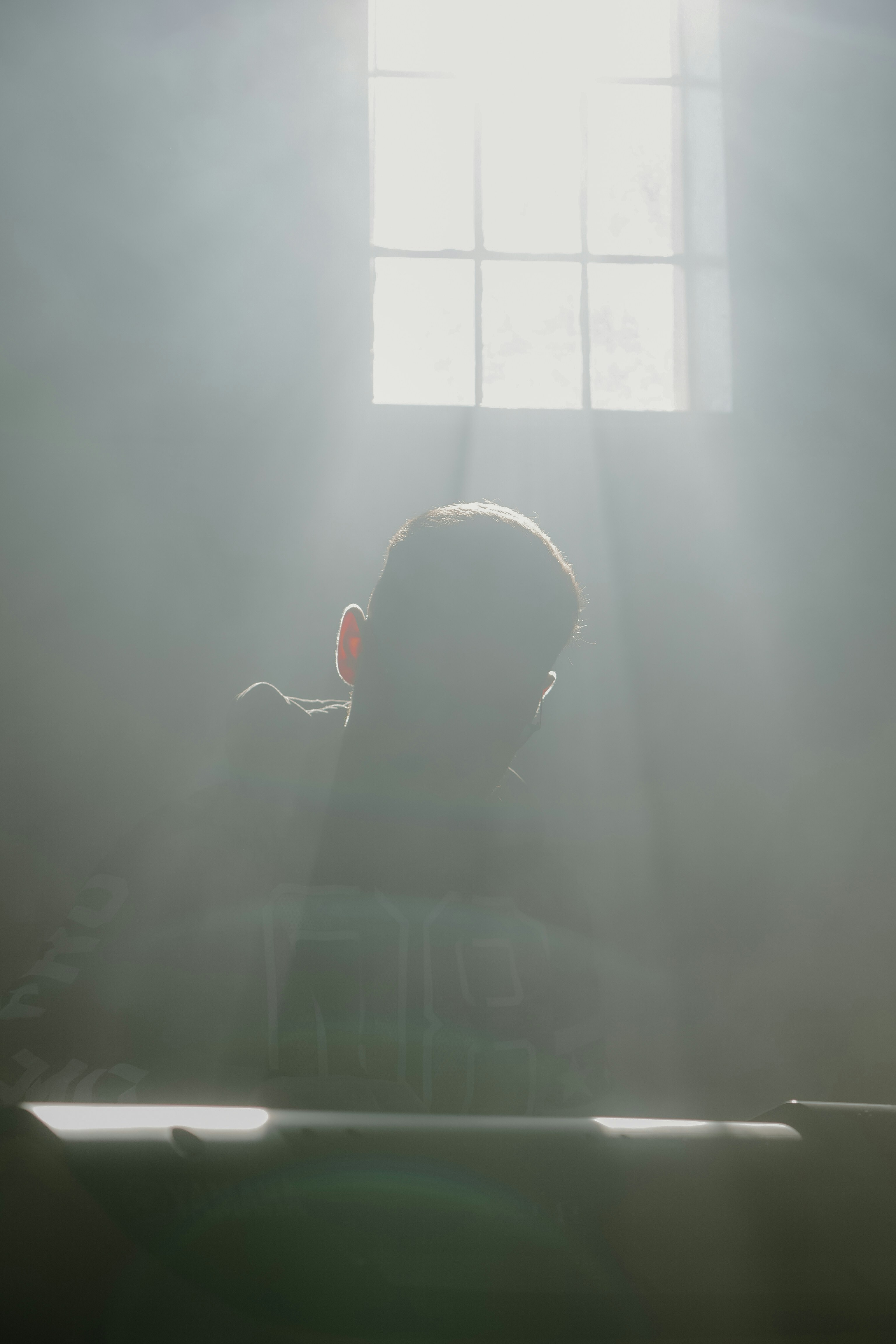 A person stands in light streaming from a window.