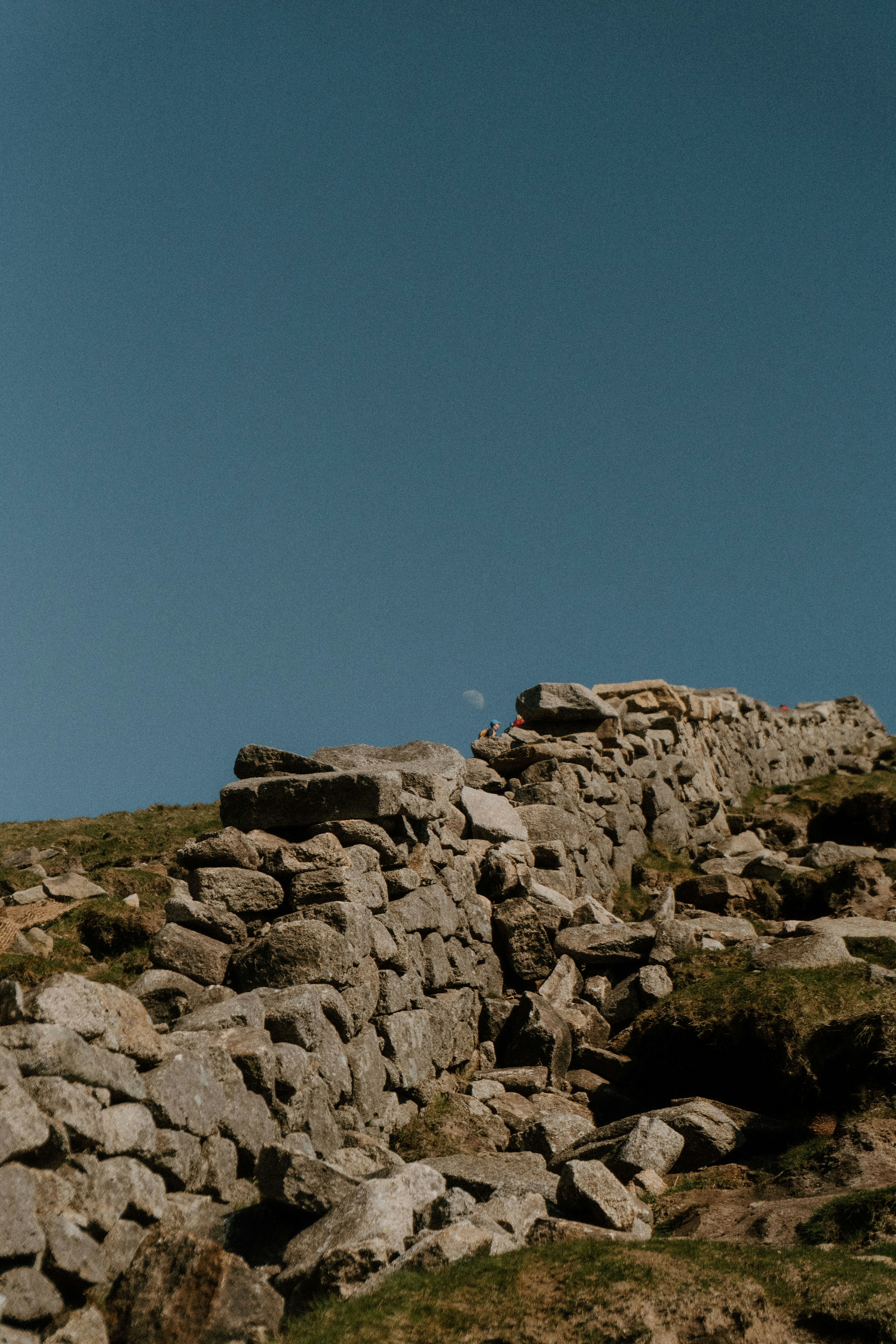 A stone wall rests under a clear, blue sky.
