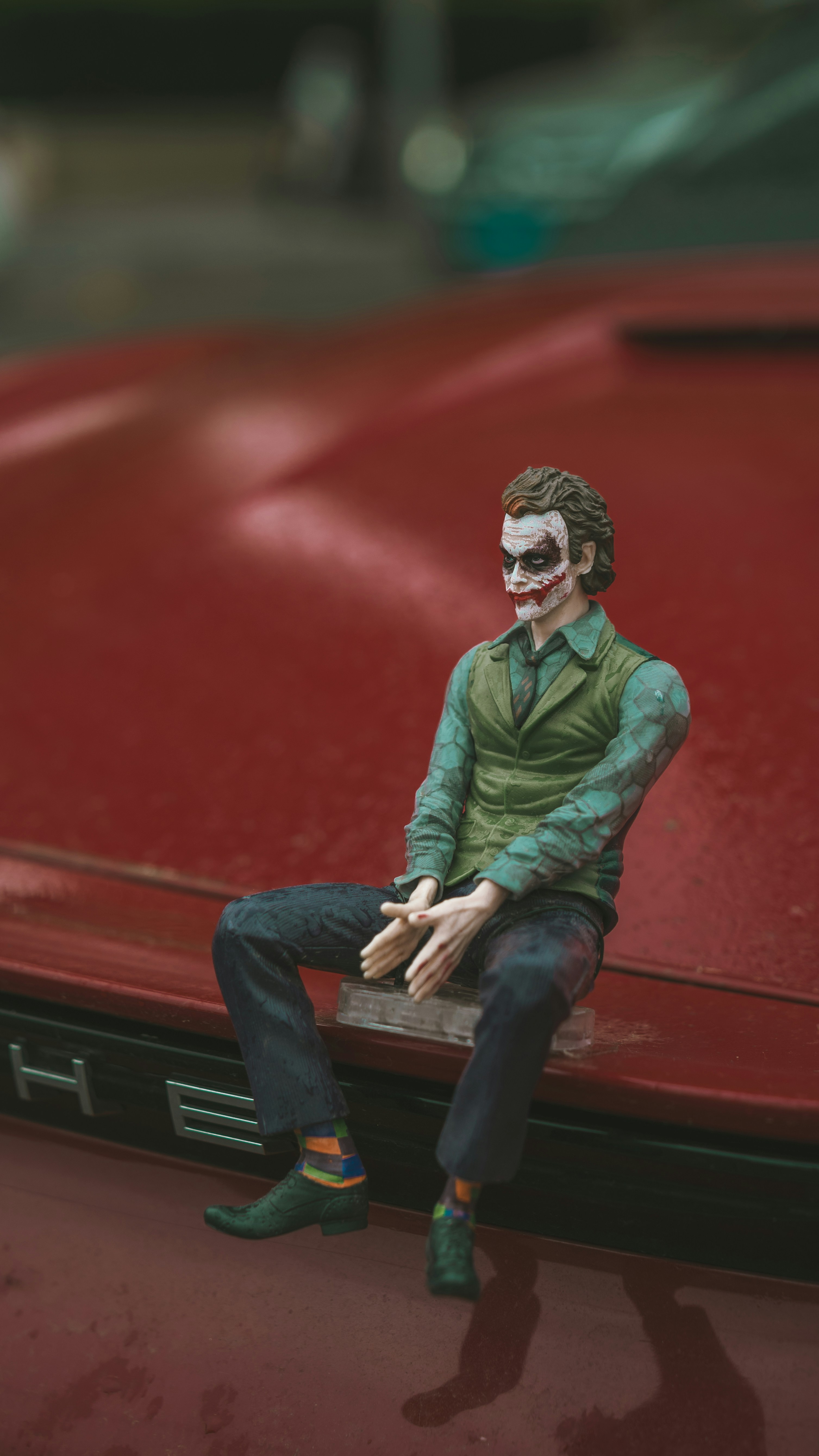 The joker figurine sits on a red car.