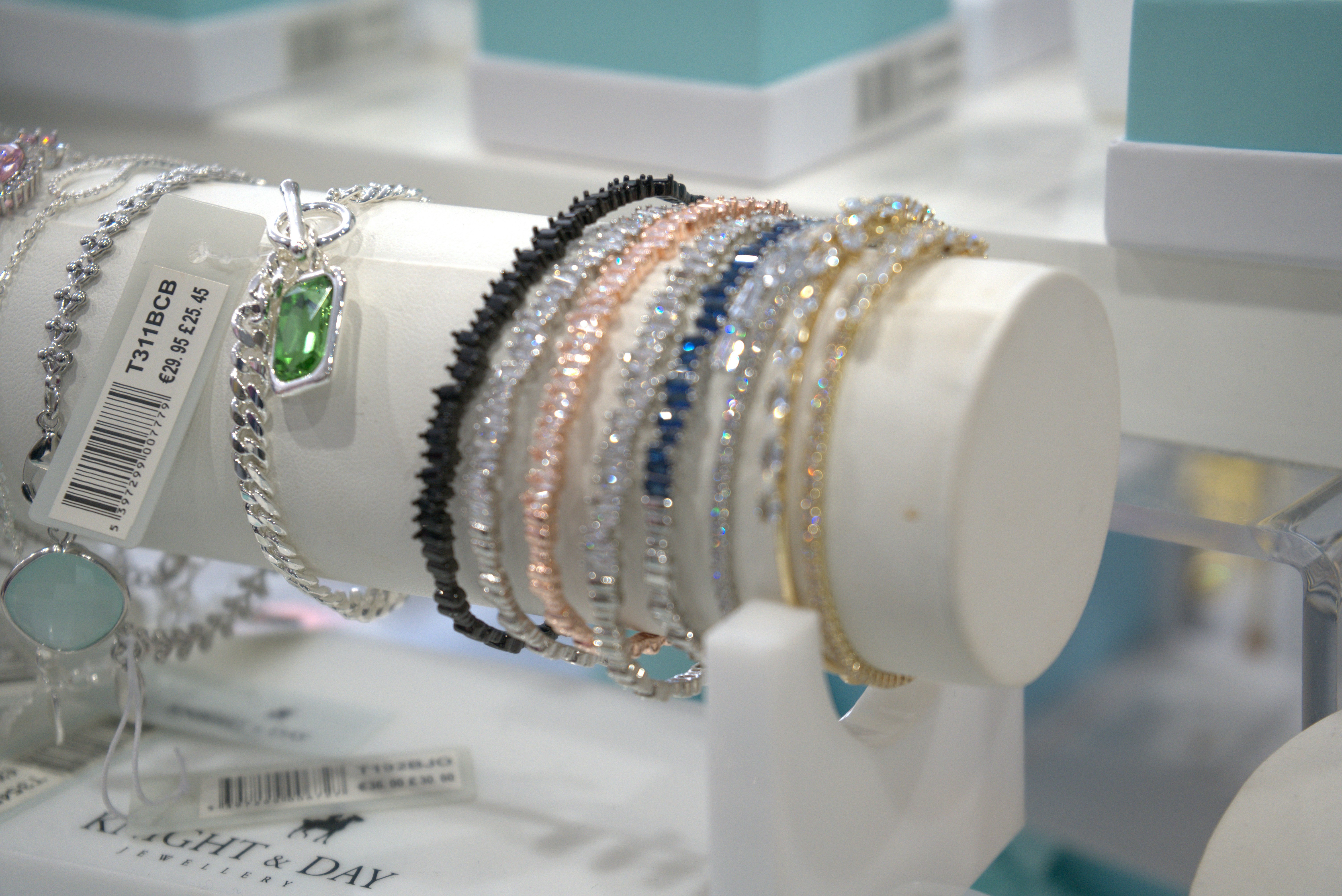 Bracelets are displayed on a white jewelry stand.