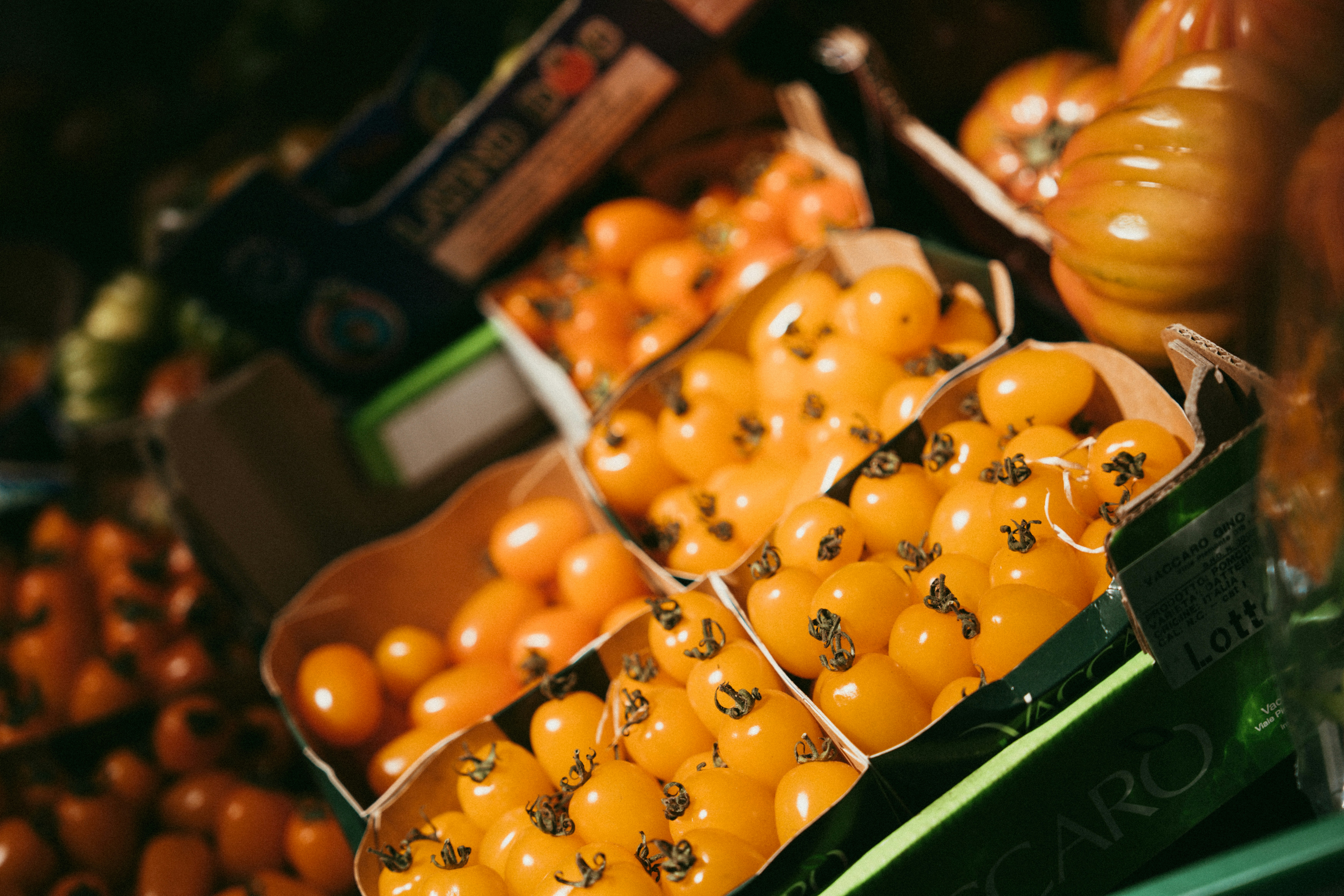 Fresh, ripe yellow tomatoes are displayed in boxes.