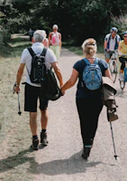 Couple holds hands while walking down a path.