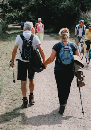 Couple holds hands while walking down a path.