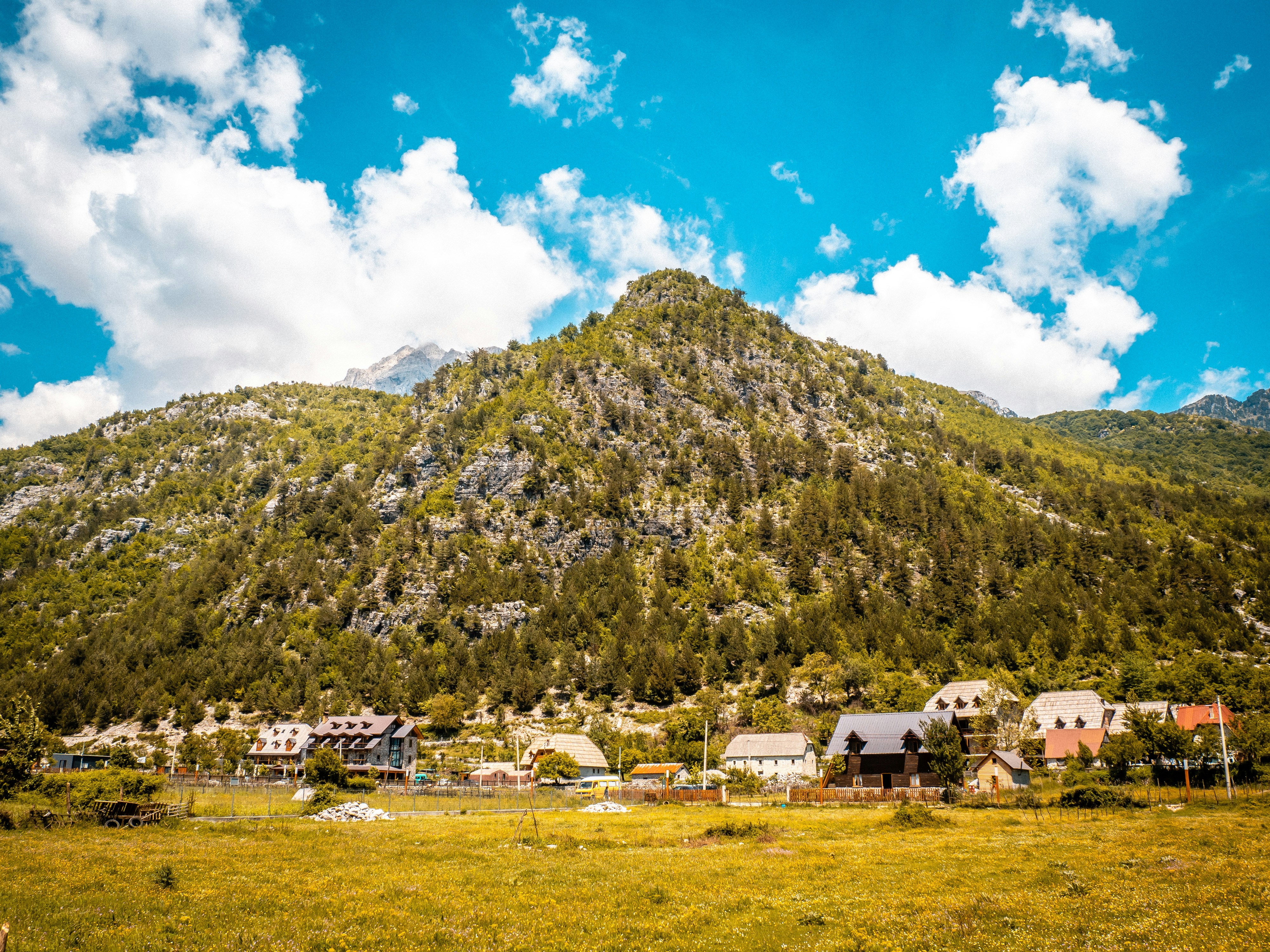 A mountain town sits beside the majestic green mountain.