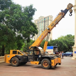 A yellow crane is parked near a building.