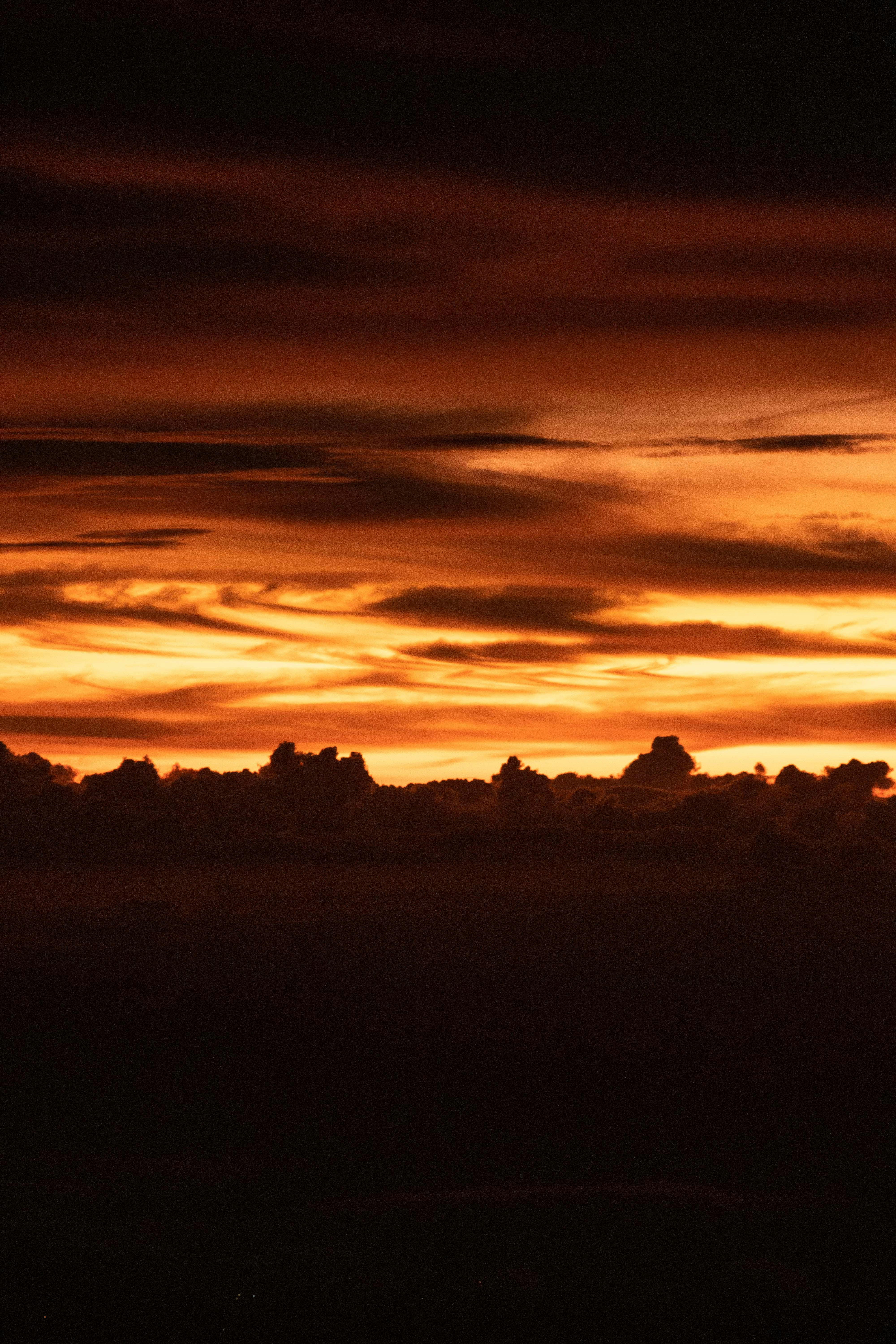 Feurige orangefarbene und schwarze Wolken dominieren den Himmel.