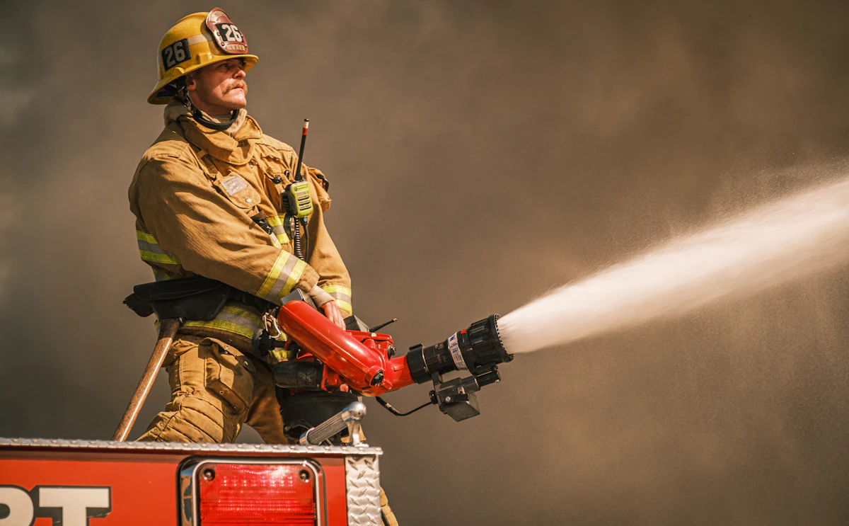 A firefighter operating a high-pressure hose at an active fire