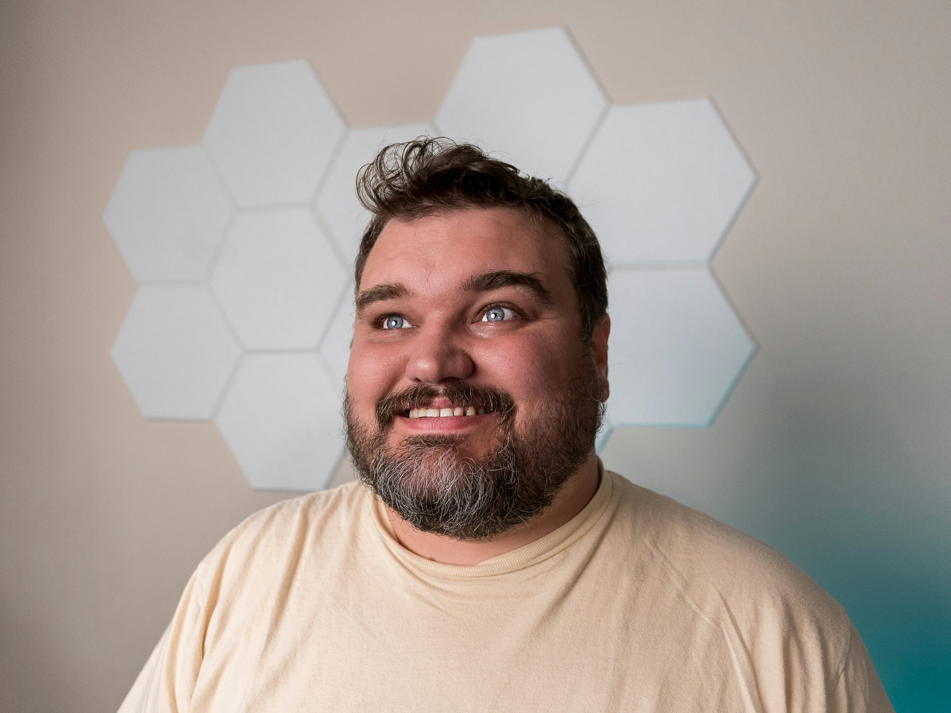 A man smiles, looking up with light-up wall tiles.