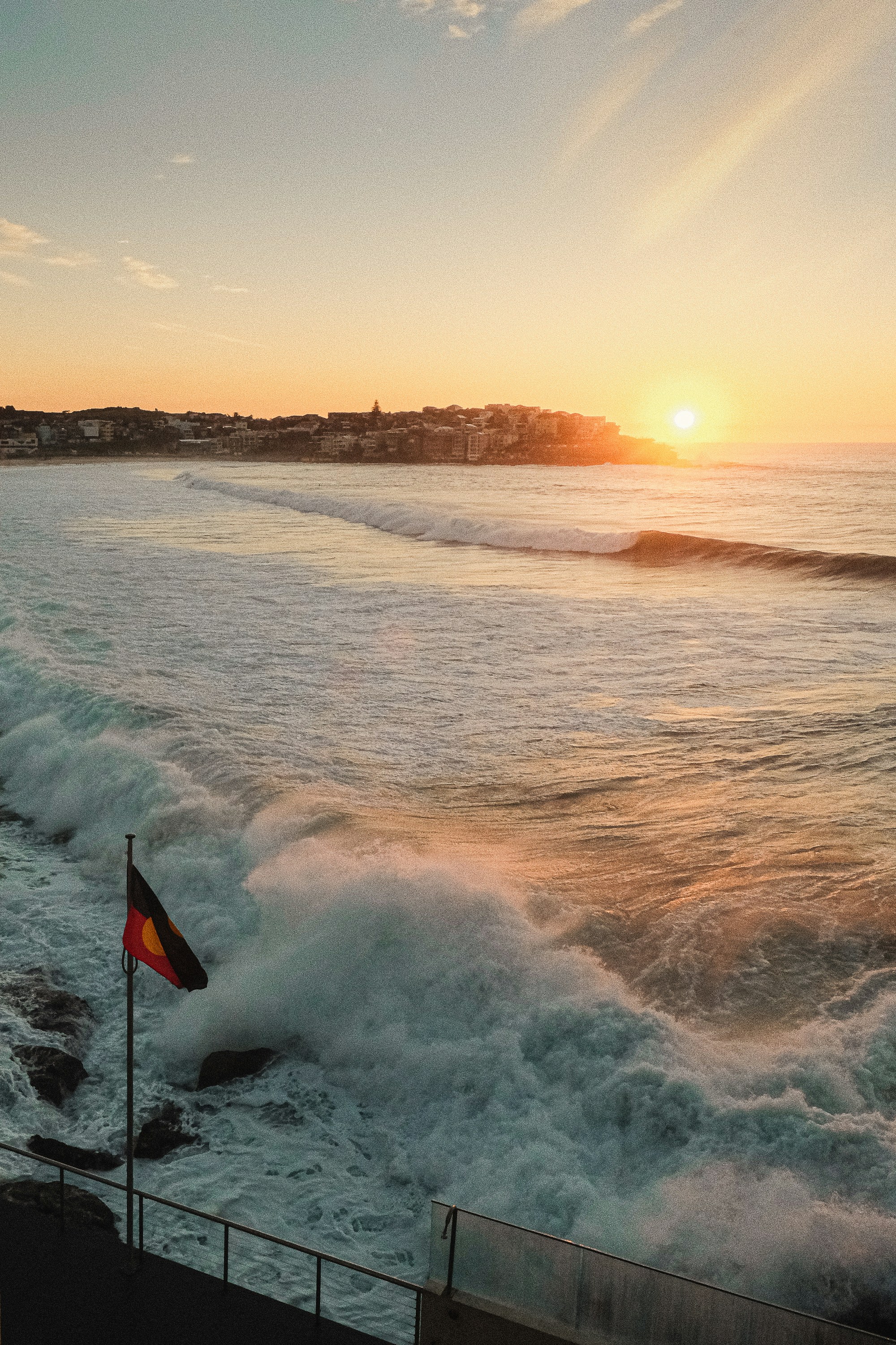 A beautiful sunrise over the ocean with the aboriginal flag.