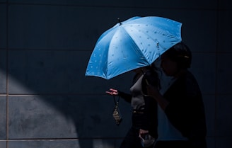 People walk together under a blue umbrella.