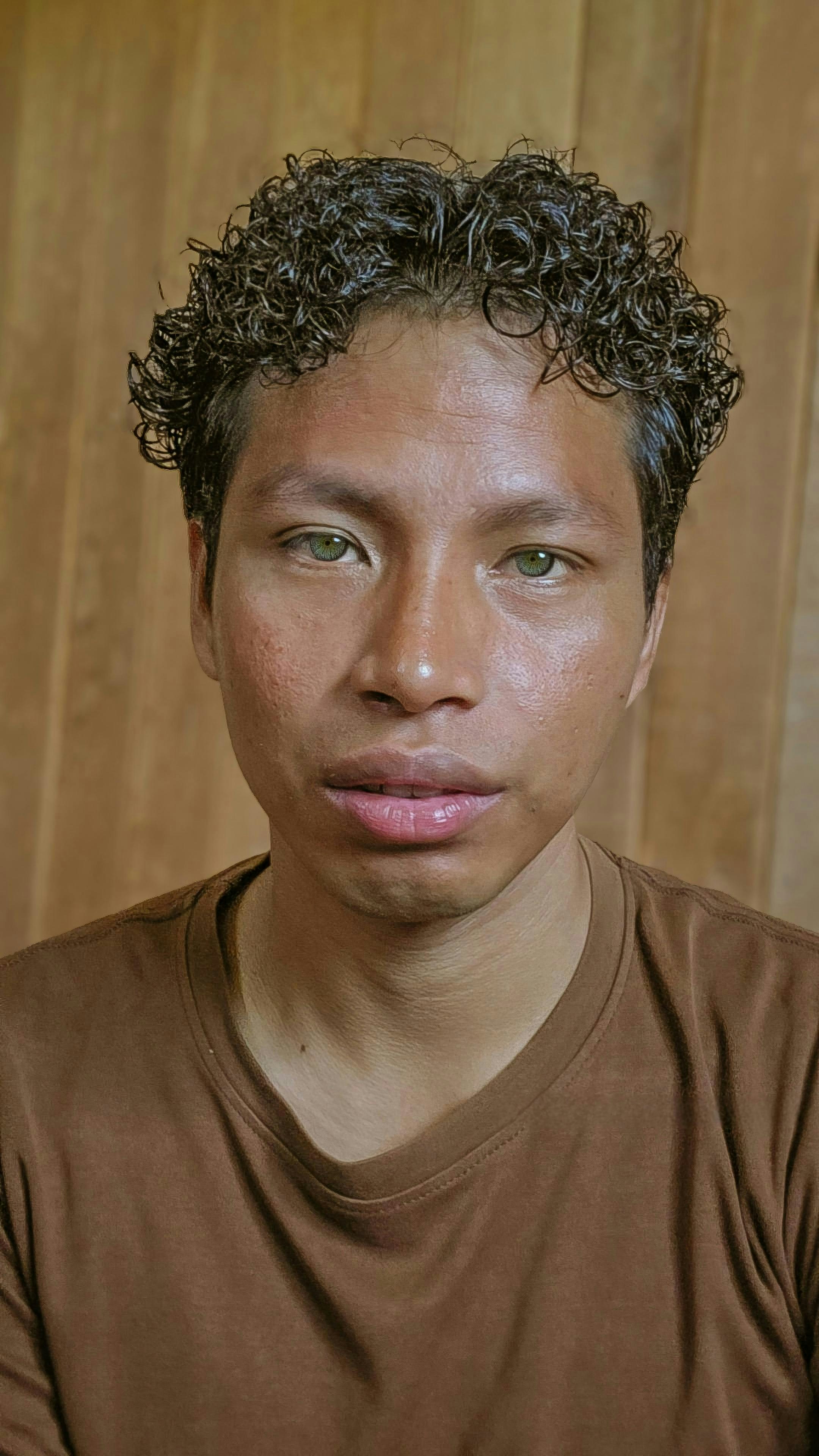 A man with curly hair looks directly at the camera.