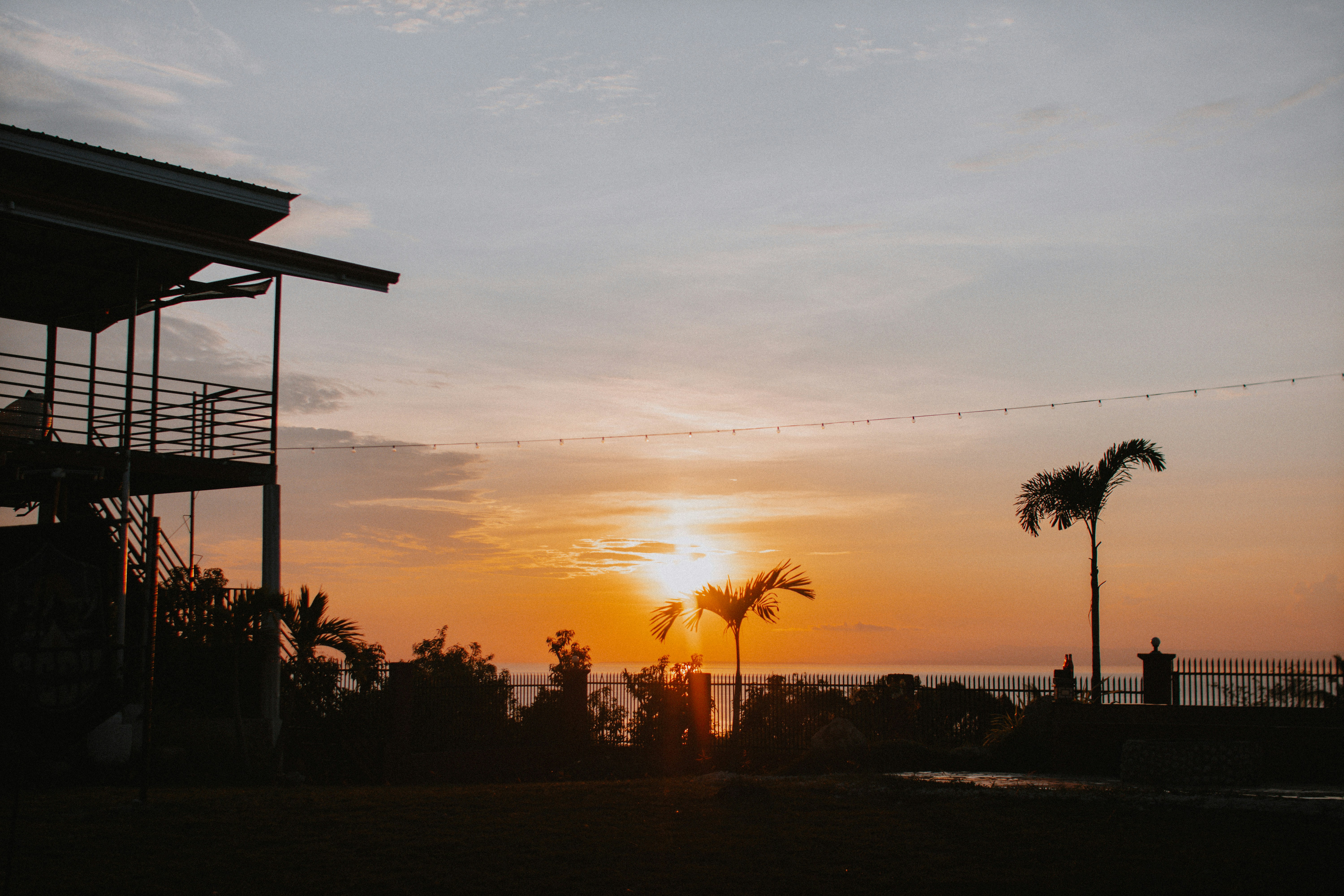 Vista del tramonto con un edificio e palme.