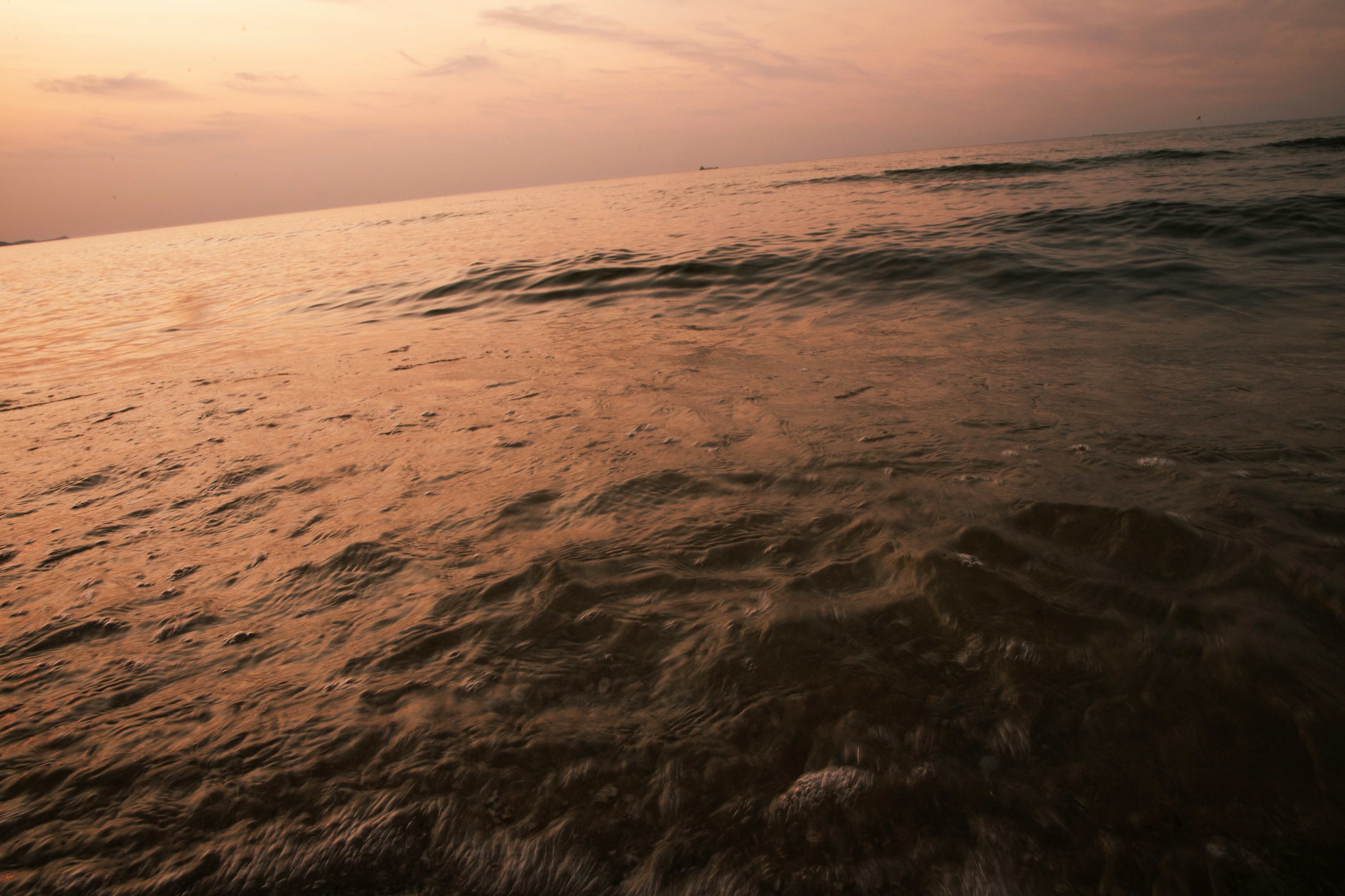 Waves gently roll at sunset over the ocean.