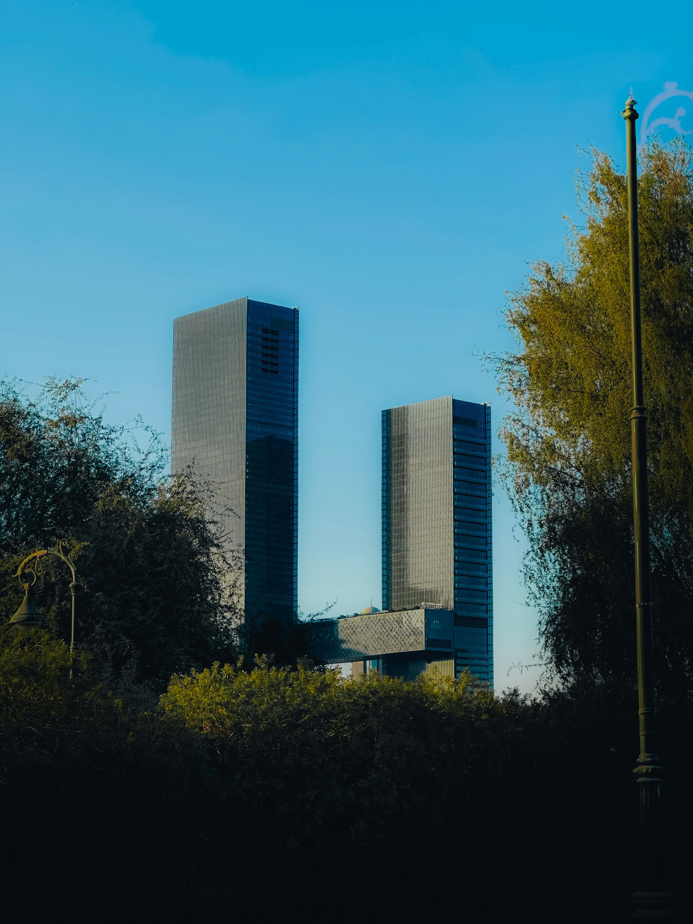 Two skyscrapers rise against a blue sky.