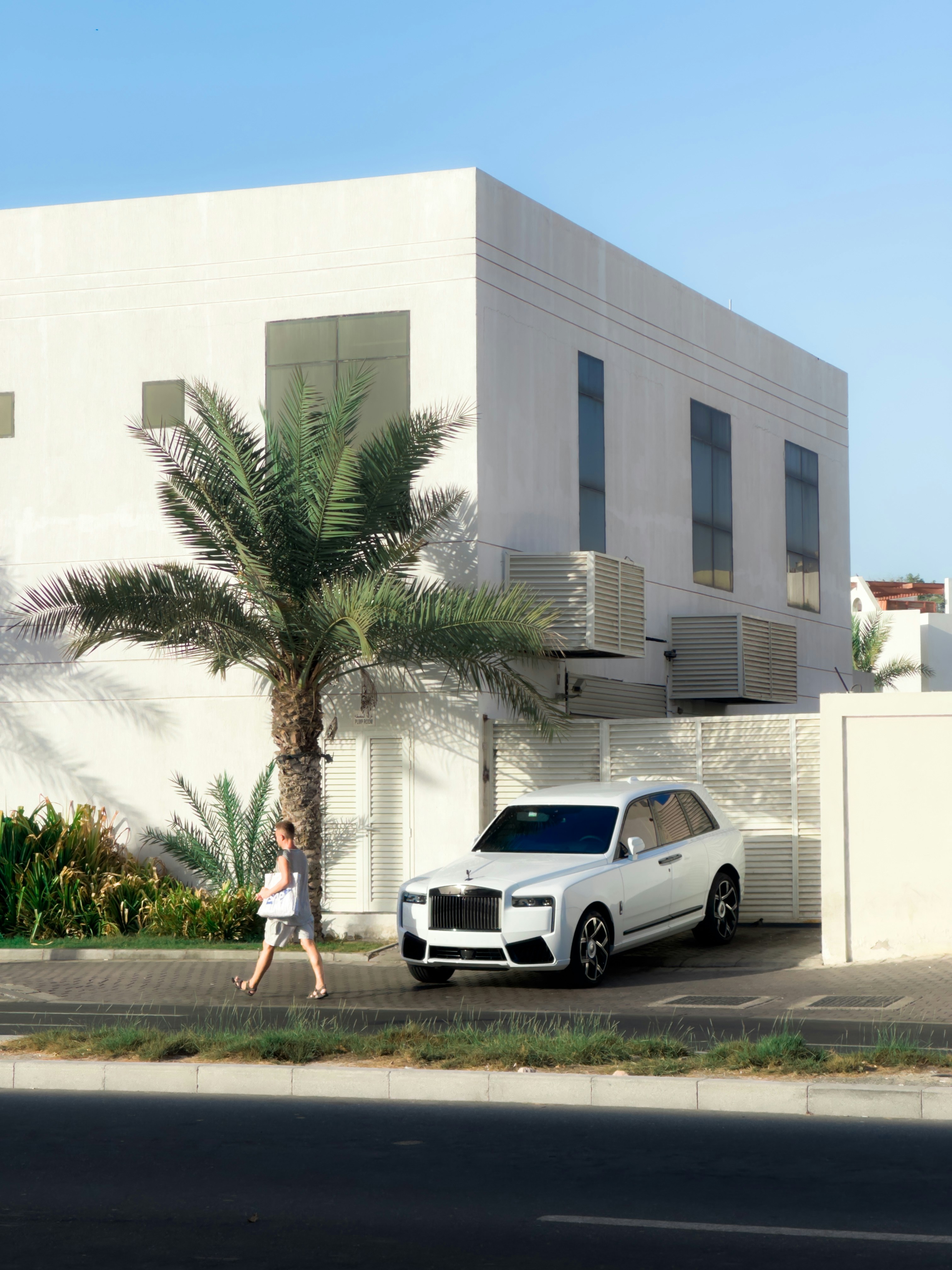 A rolls-royce parked near a modern white house.