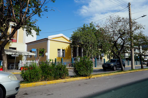A yellow building stands near green trees.