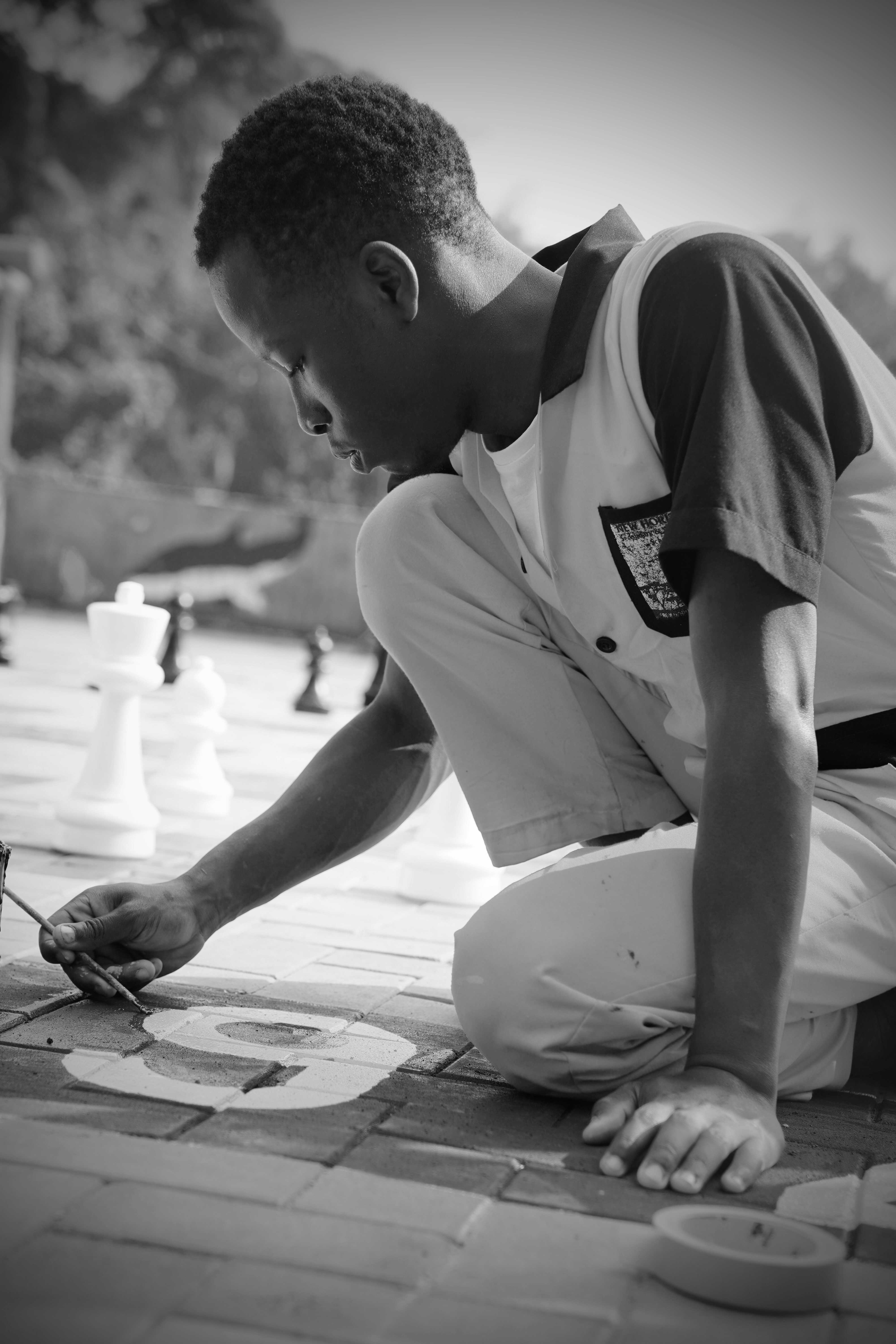 A young man paints on a giant chessboard