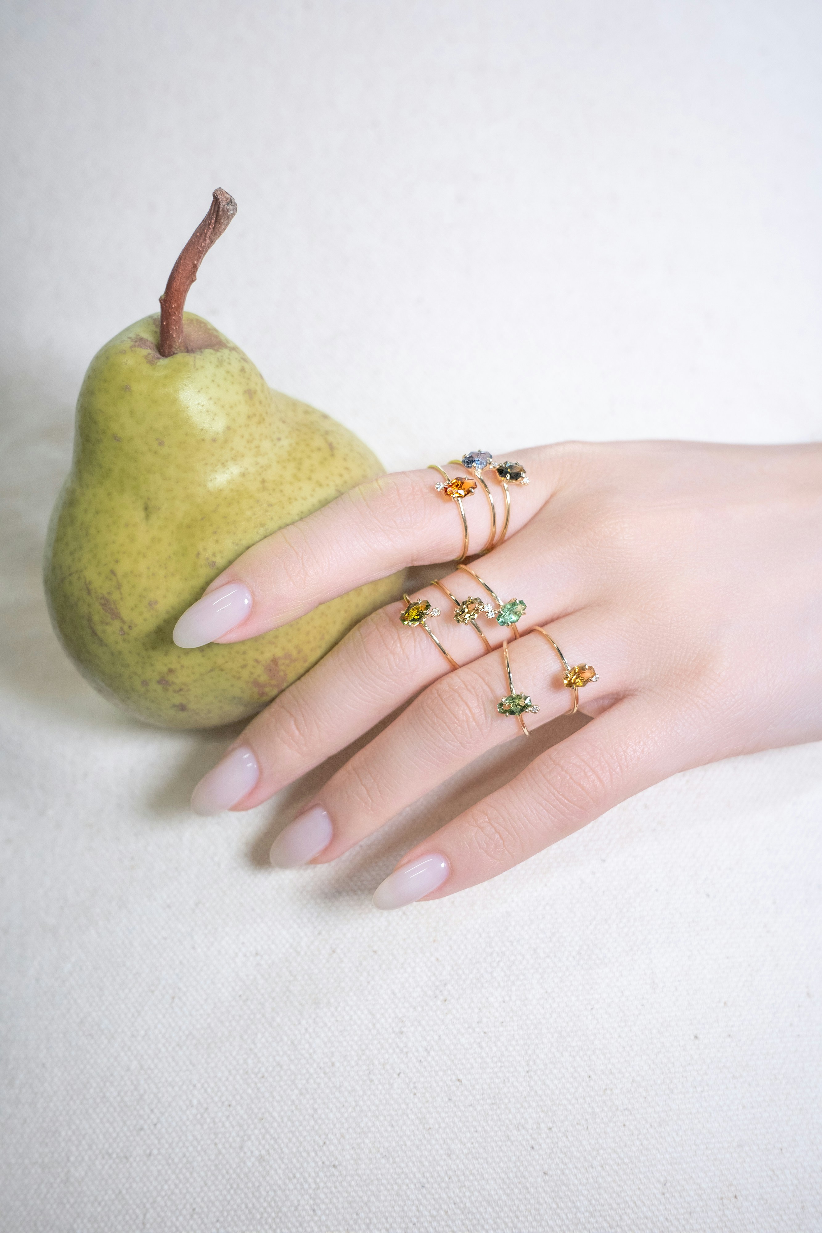 Schmuckringe befinden sich an einer Hand in der Nähe einer Birne.